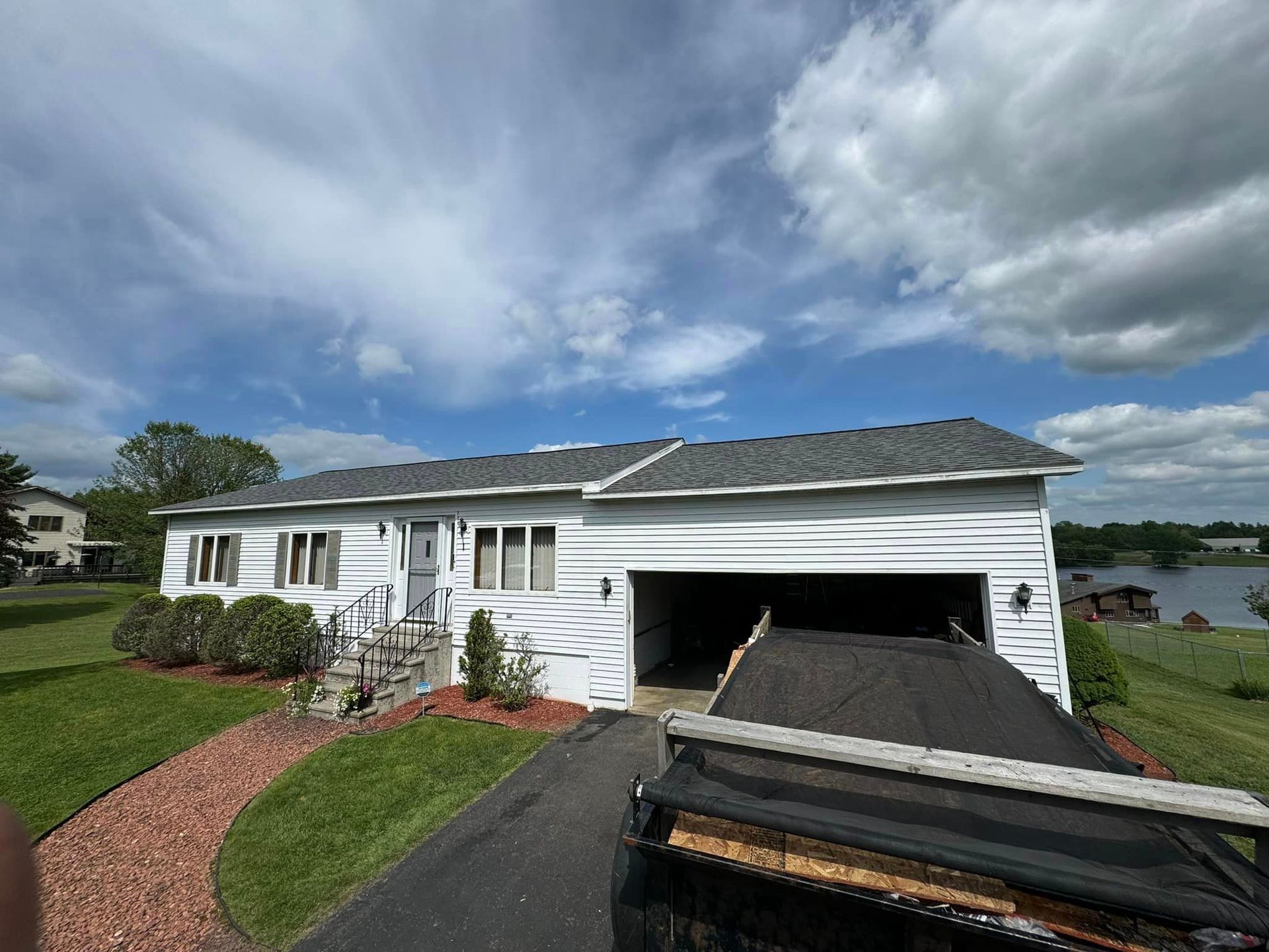 A white house with a gray roof and a driveway