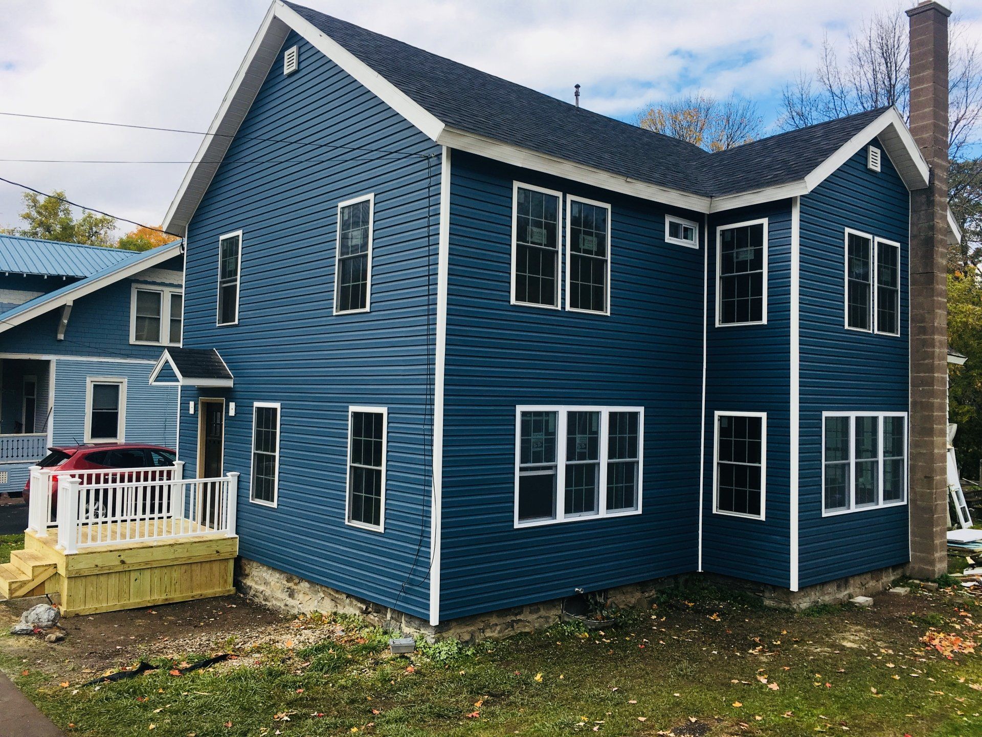 A blue house with a lot of windows and a car parked in front of it.