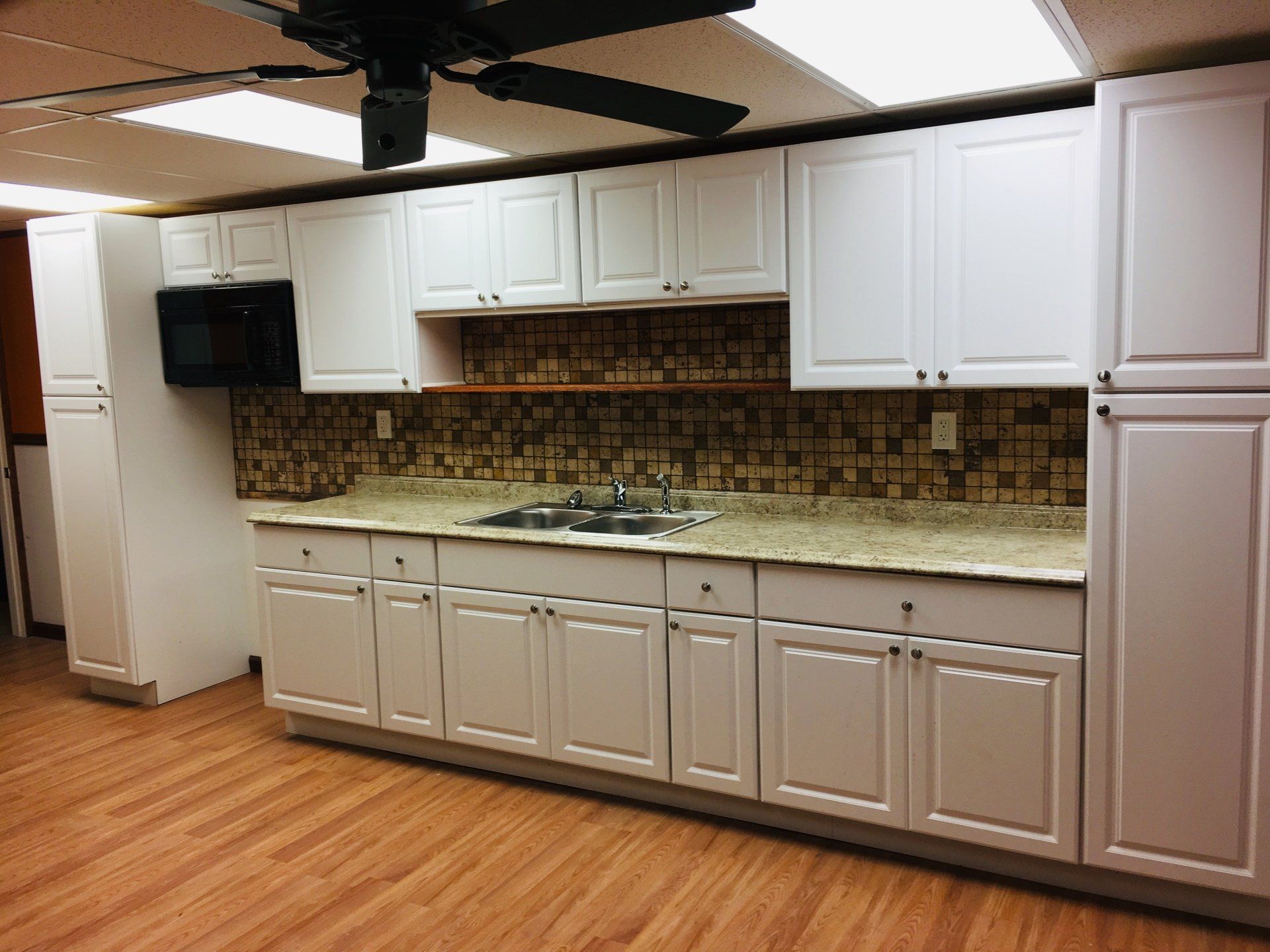 A kitchen with white cabinets and a sink.