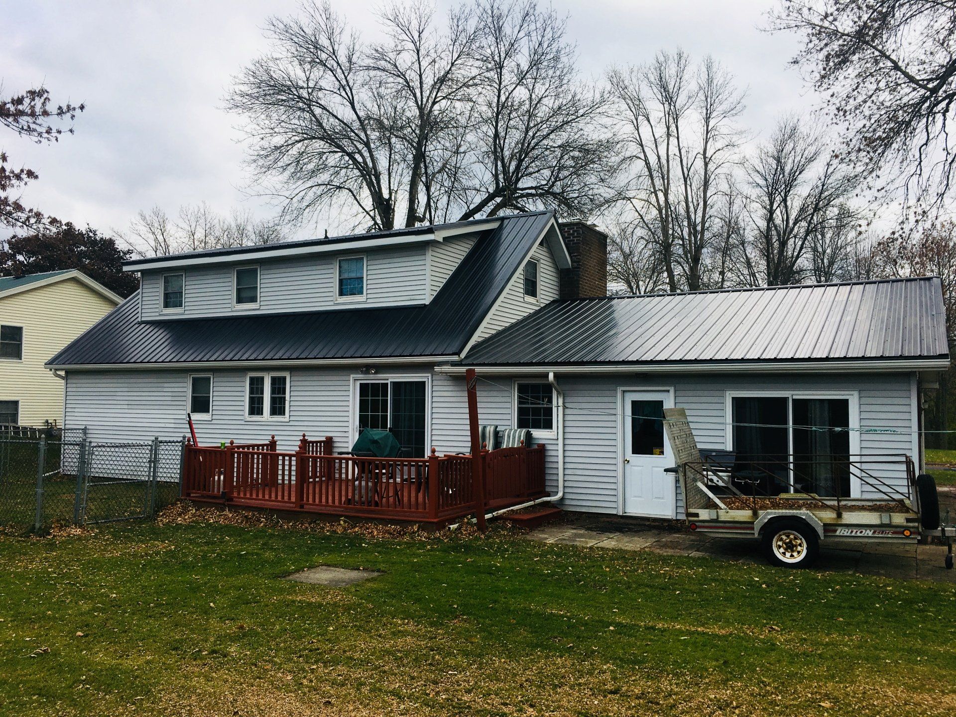 A white house with a metal roof and a trailer parked in front of it