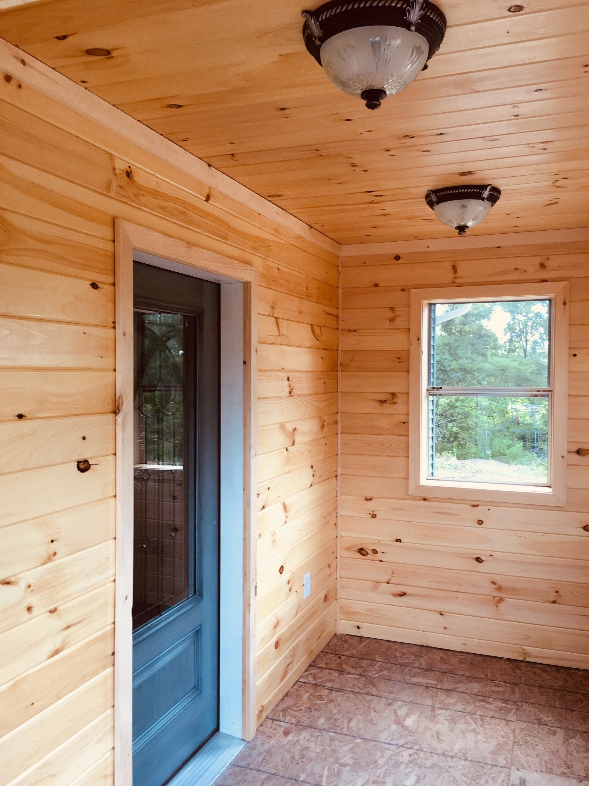 A wooden room with a door and two windows