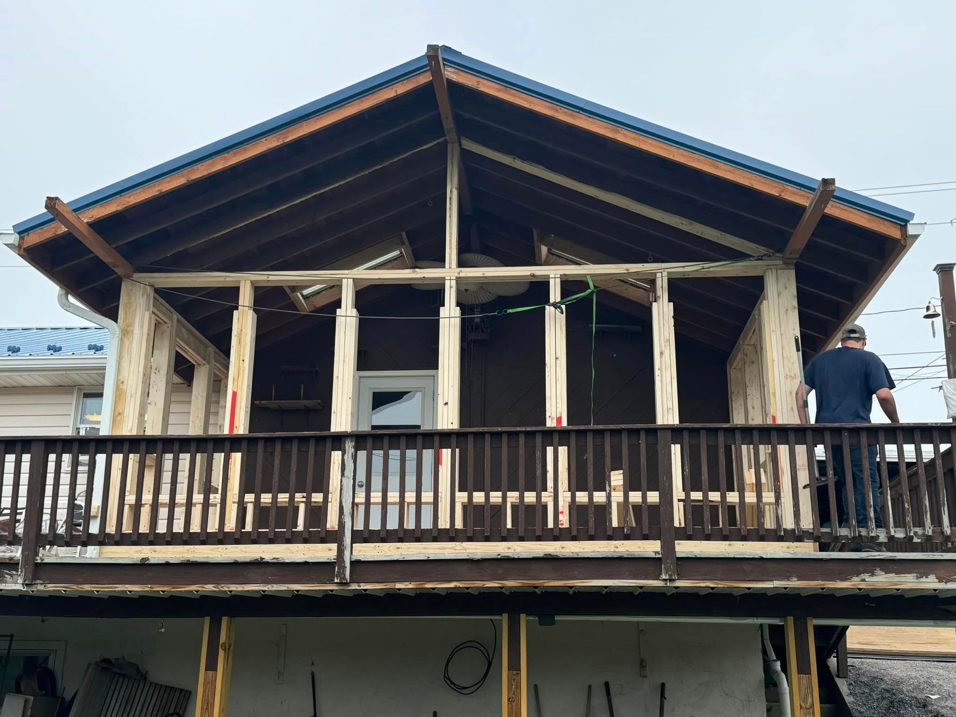 A man is standing on a balcony of a house under construction.
