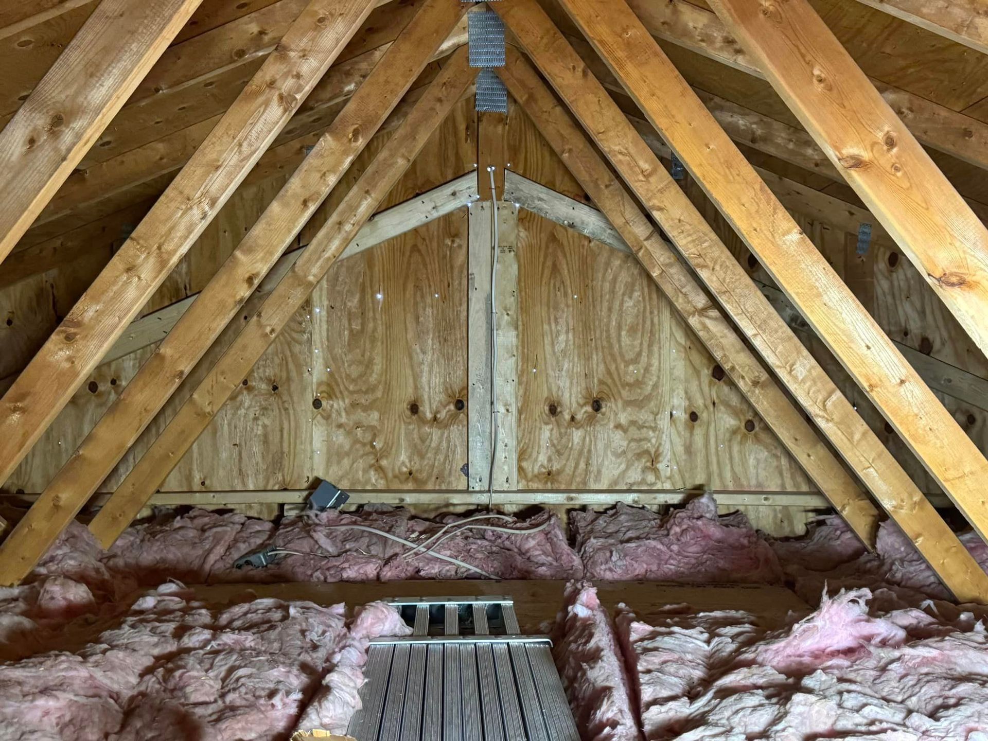 The attic of a house with wooden beams and insulation.