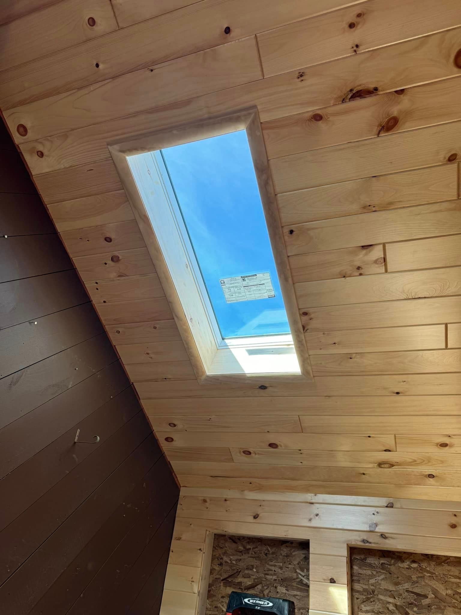 A wooden ceiling with a skylight in the middle of it.