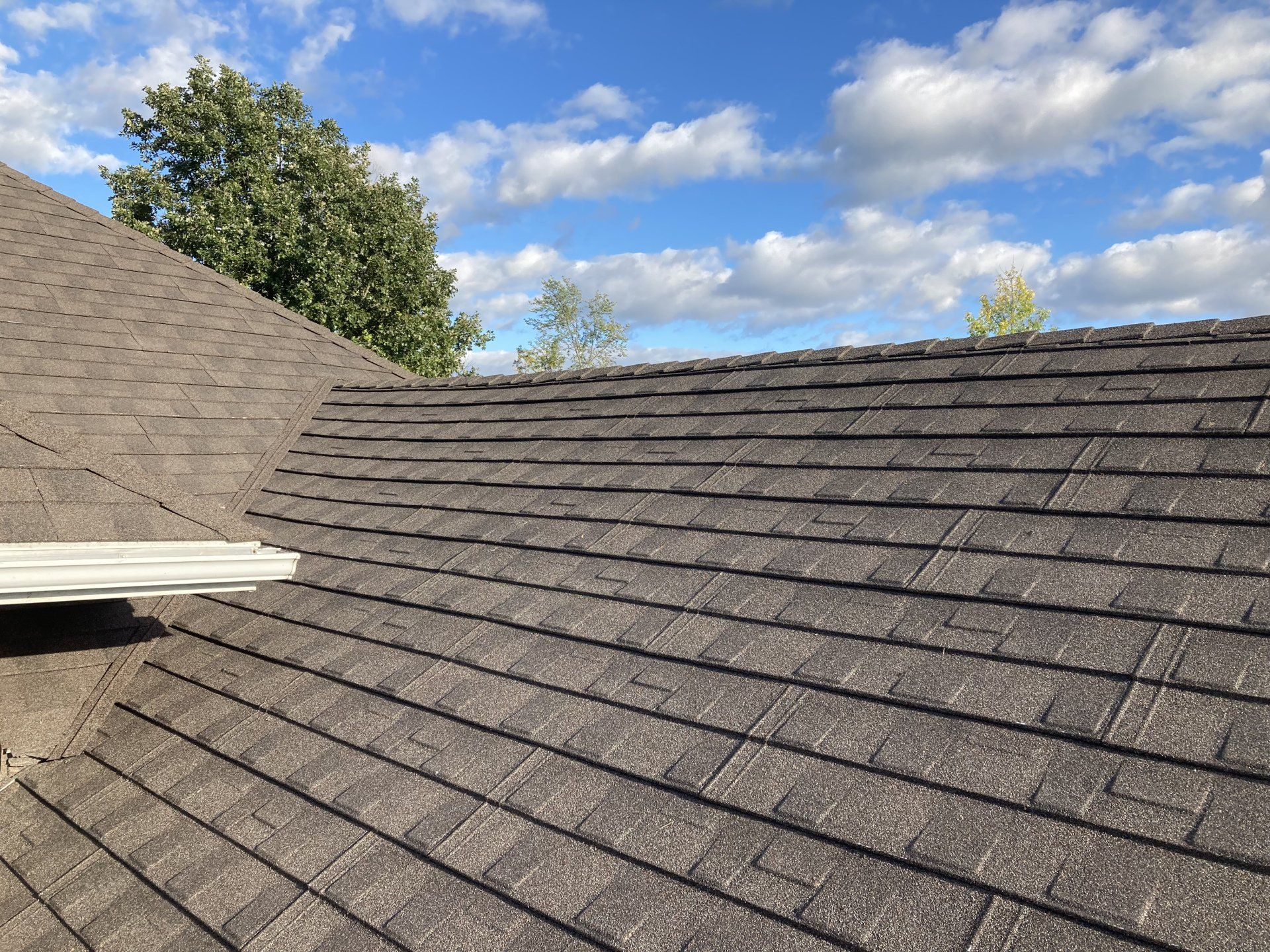 A close up of a roof with a blue sky and clouds in the background.