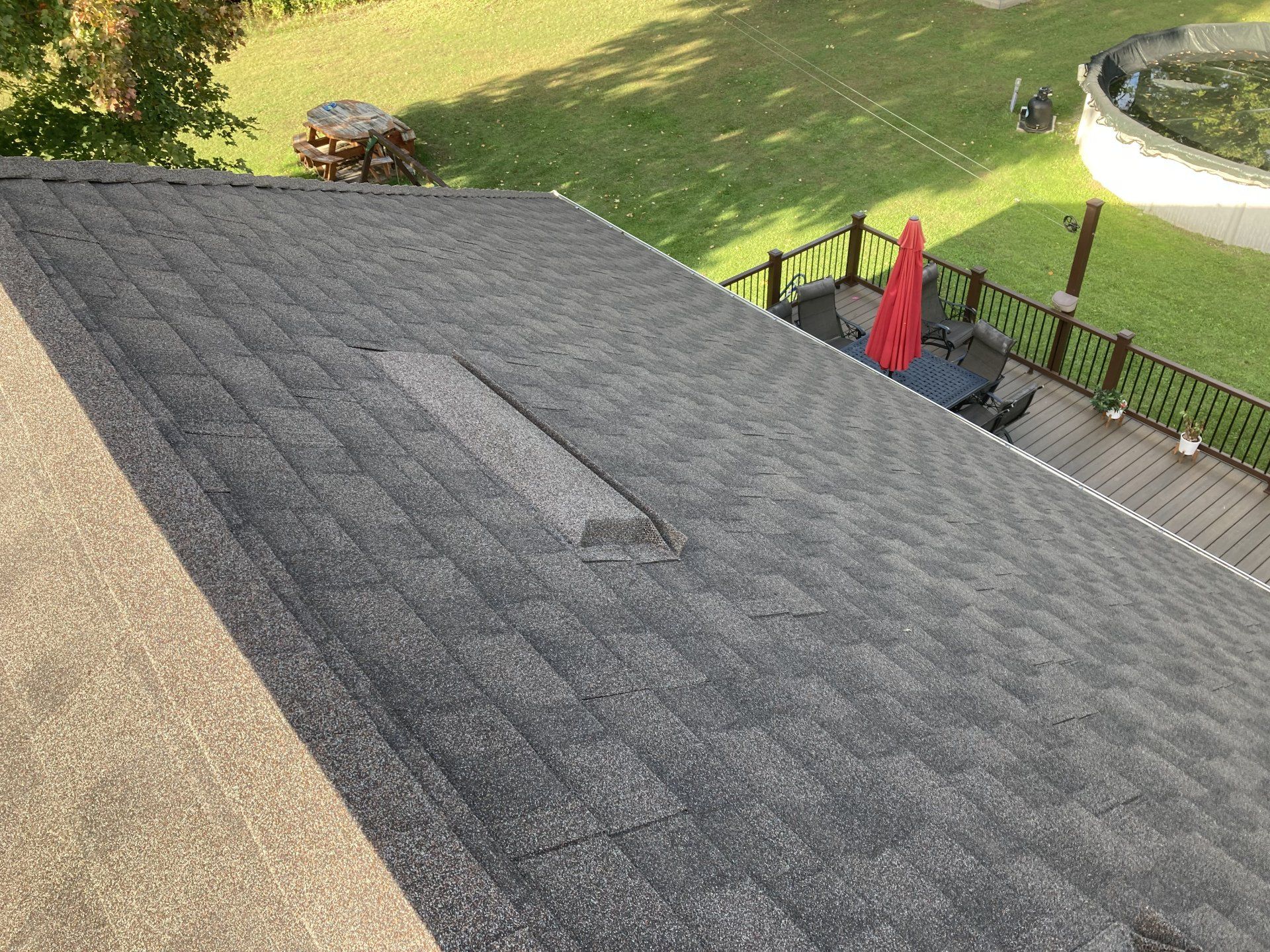 An aerial view of a roof with a deck and lawn in the background.