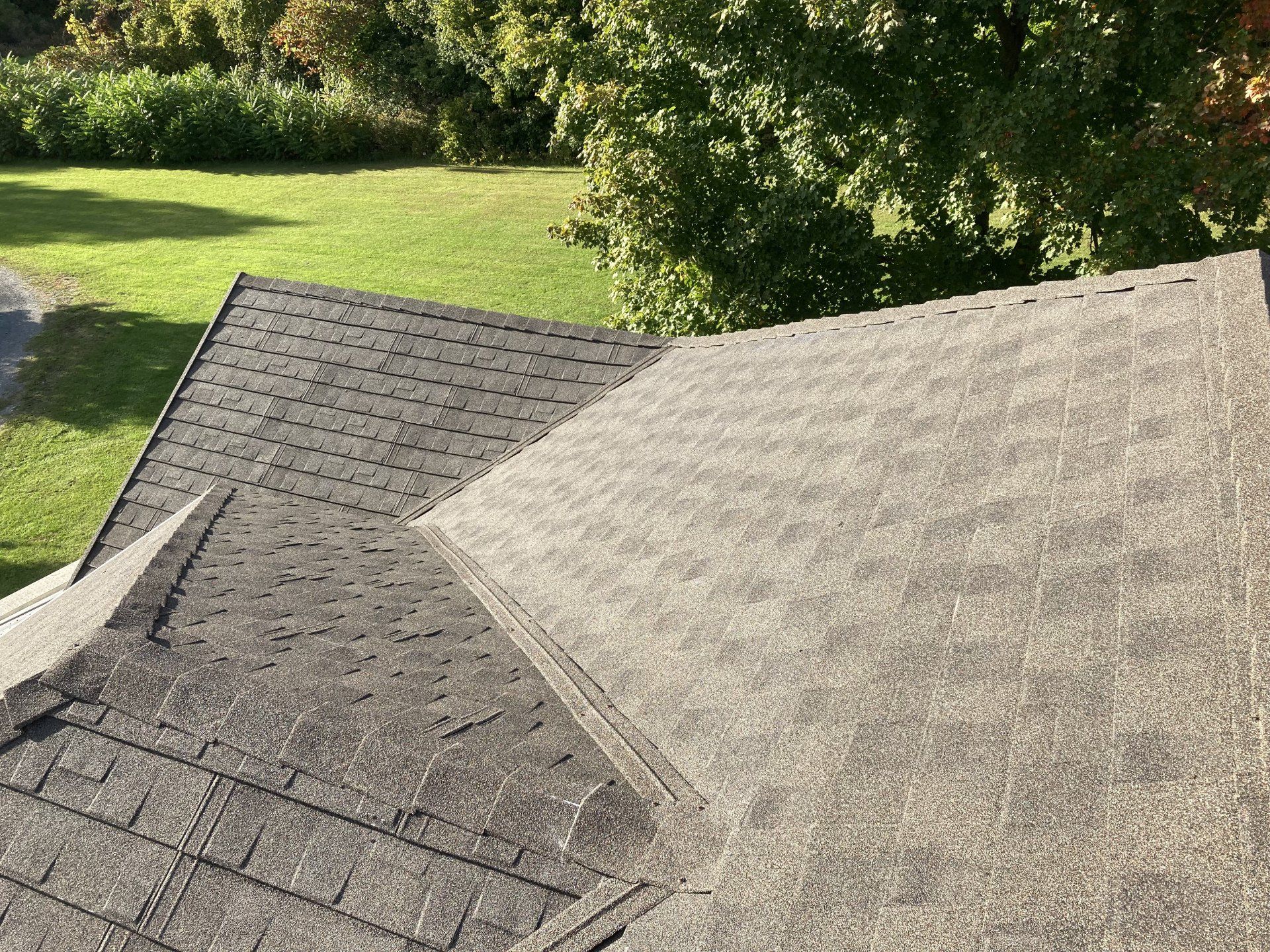 A roof with a lot of shingles on it and trees in the background.