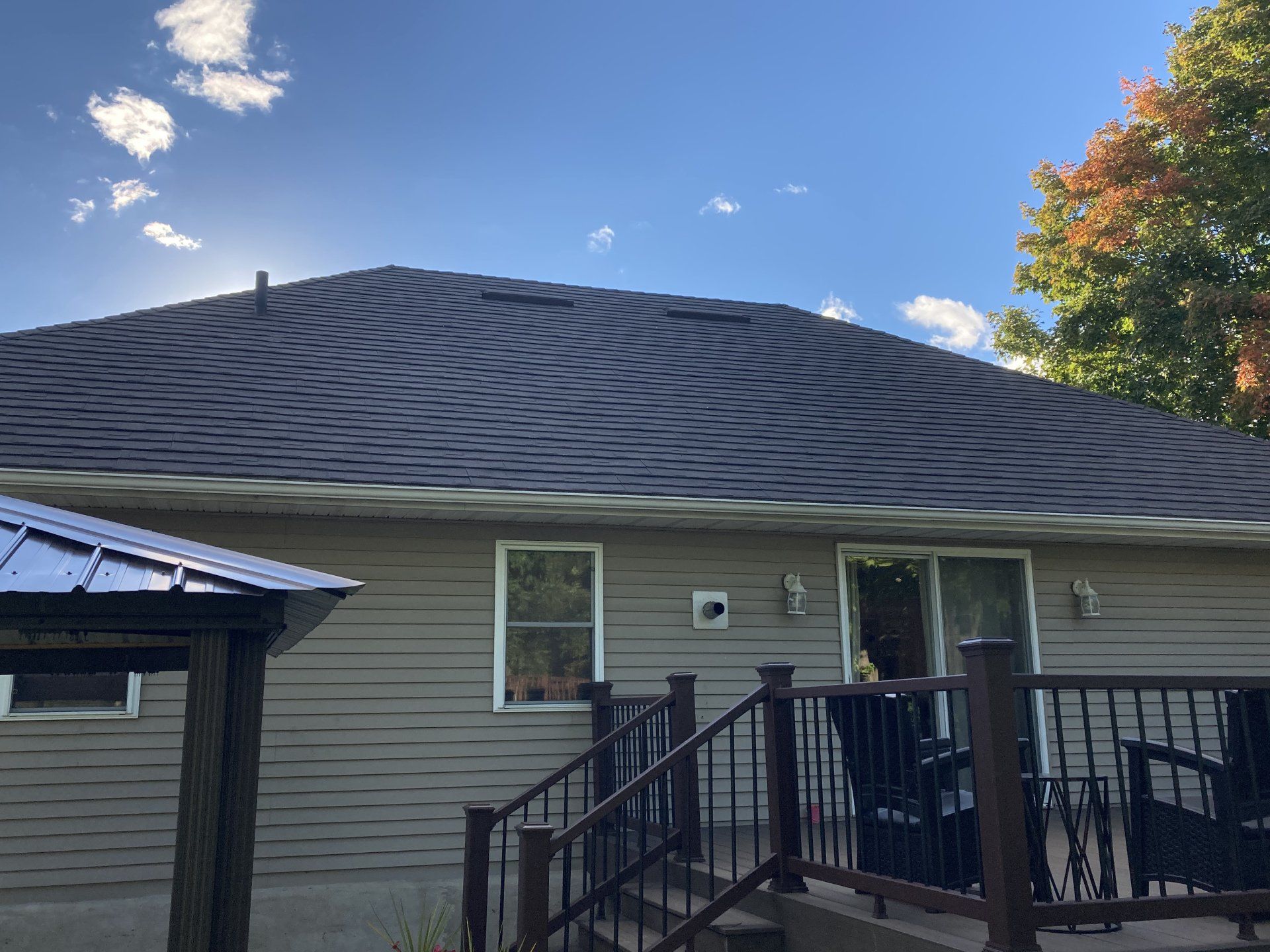 The back of a house with a deck and stairs leading to it.