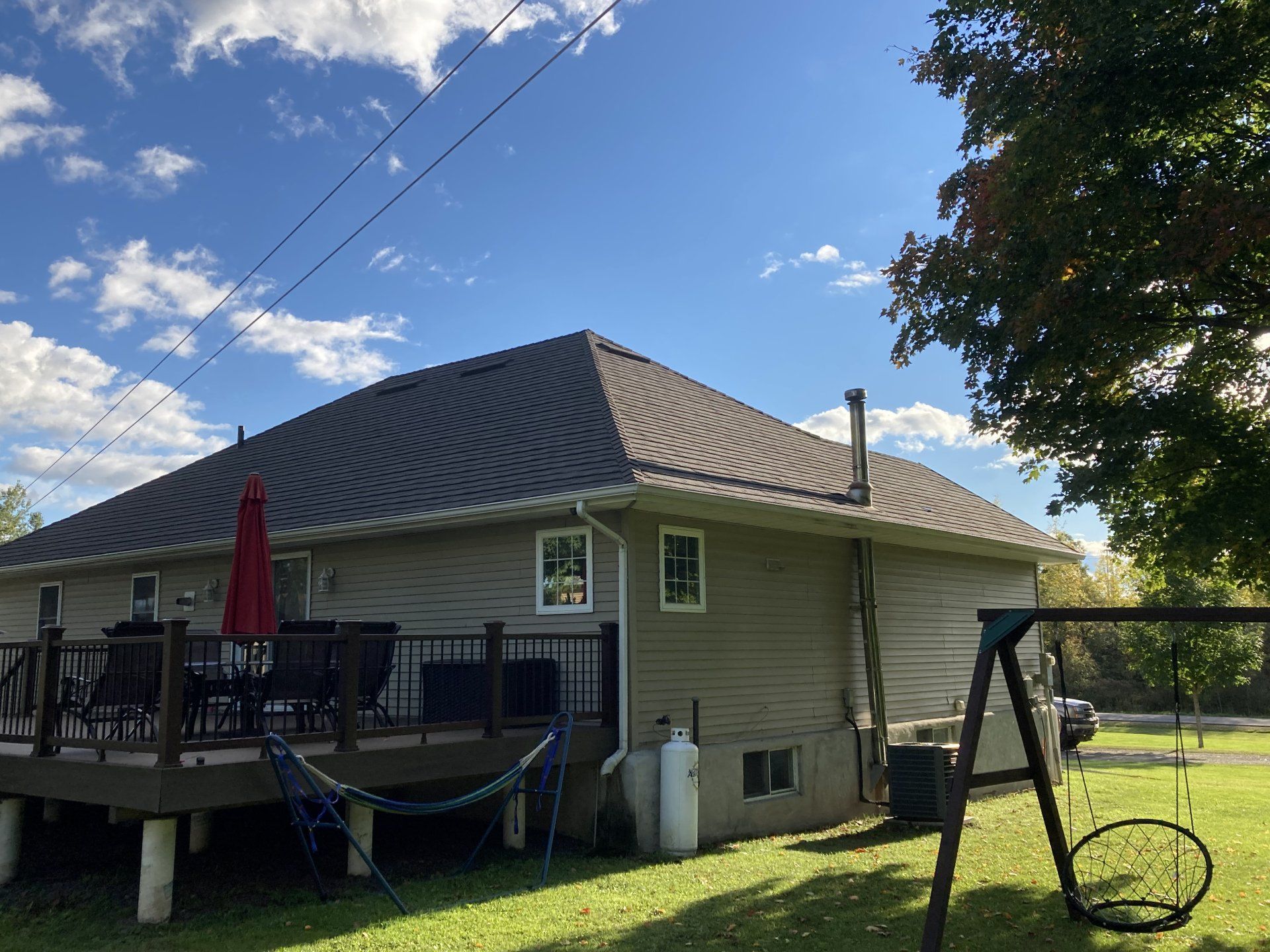 A house with a deck and a swing set in the backyard.
