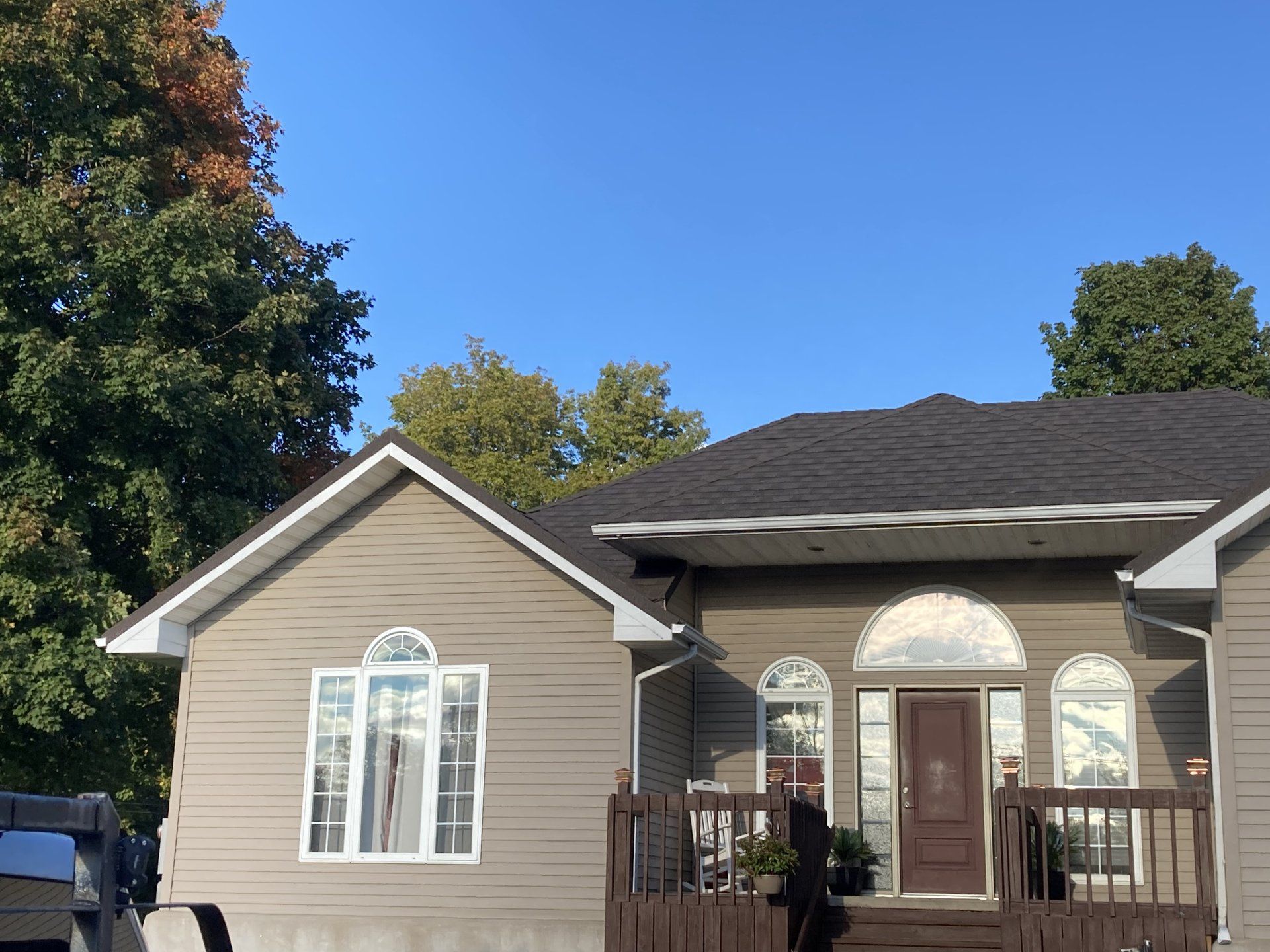 A small house with a porch and a car parked in front of it.
