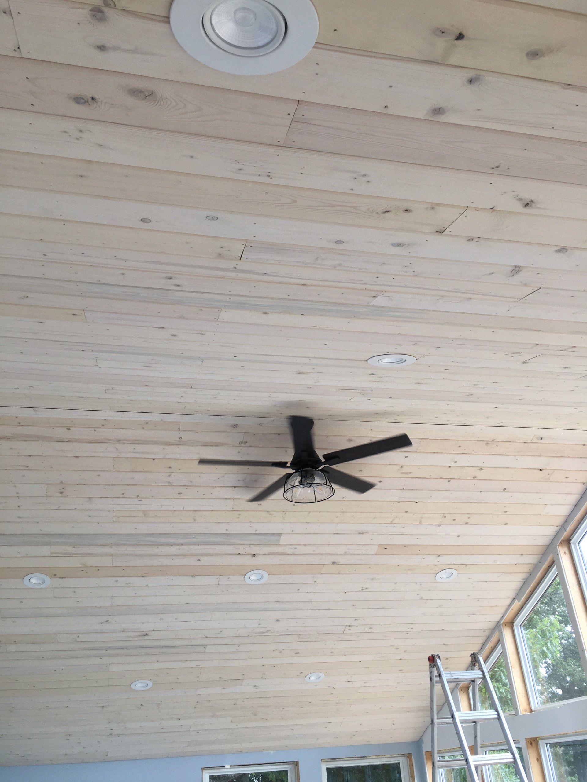 A wooden ceiling with a ceiling fan hanging from it