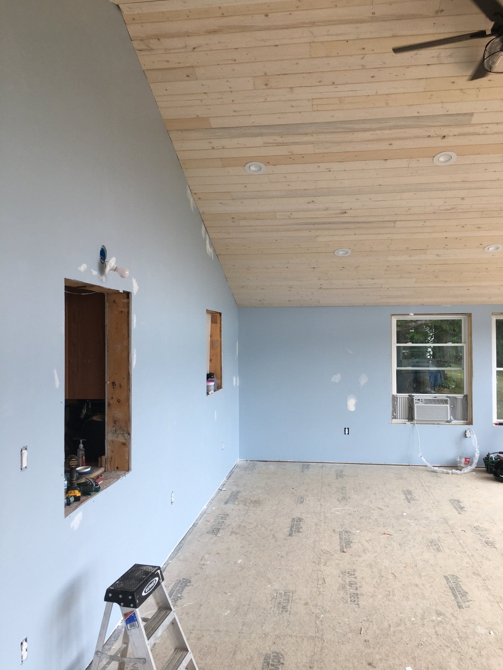 An empty room with a ladder and a ceiling fan