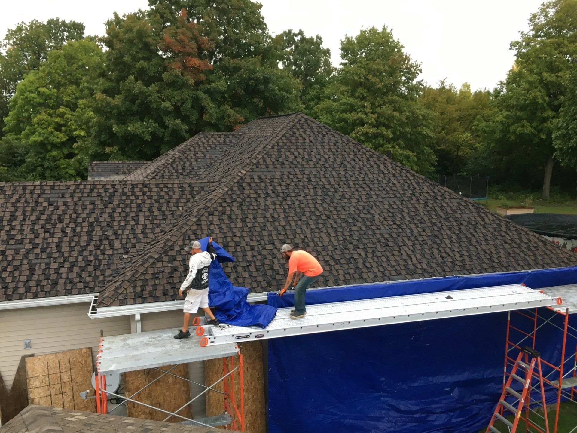 Two men are working on the roof of a house.
