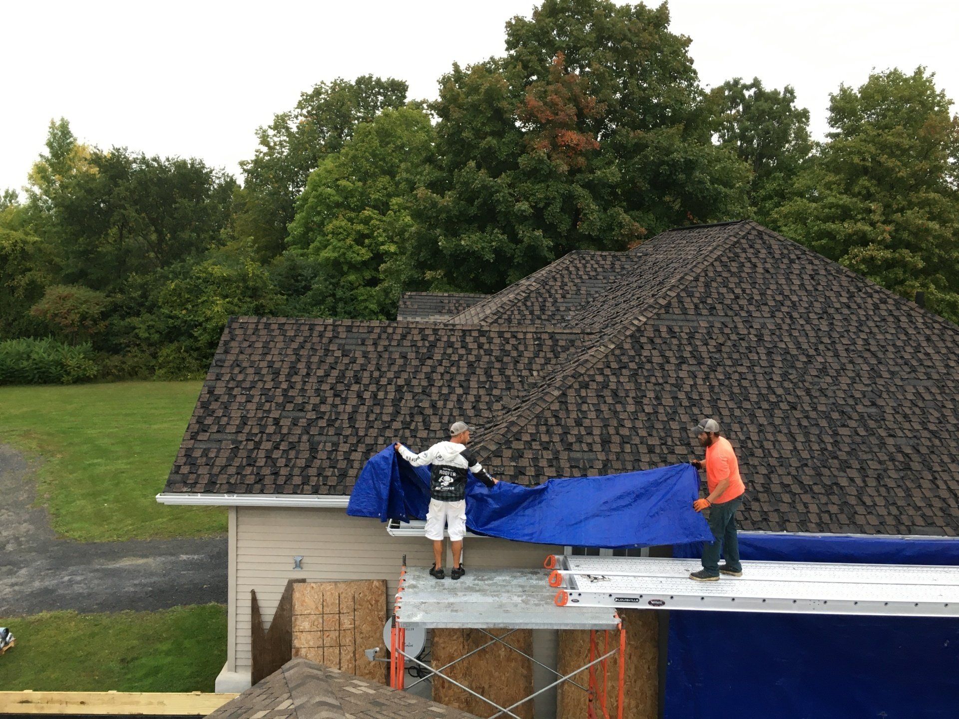 Two men are working on the roof of a house.