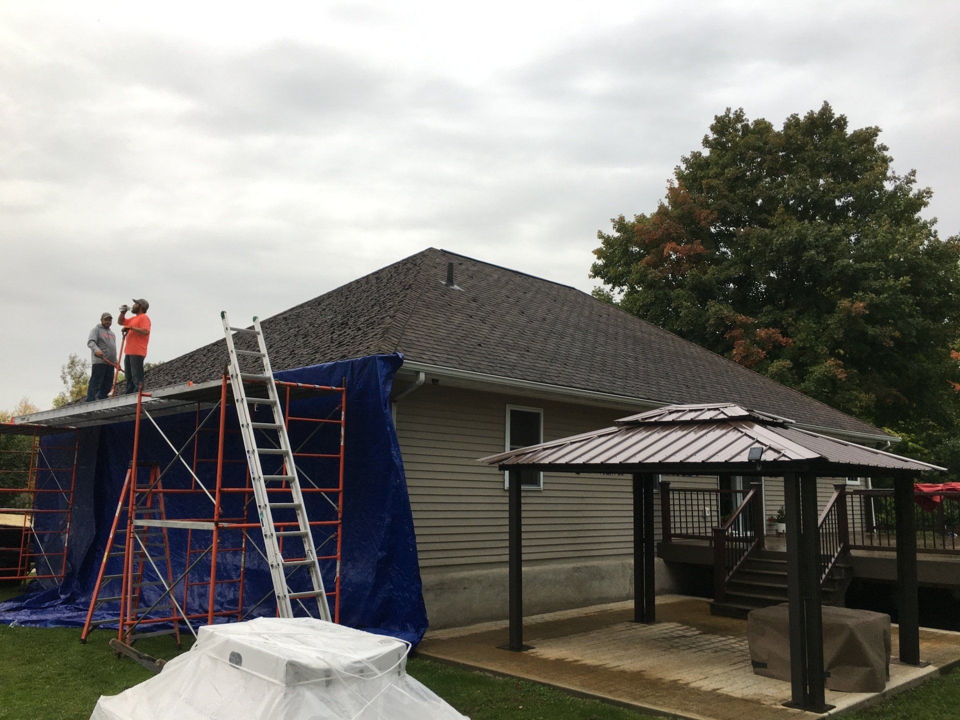 A group of people are working on the roof of a house.