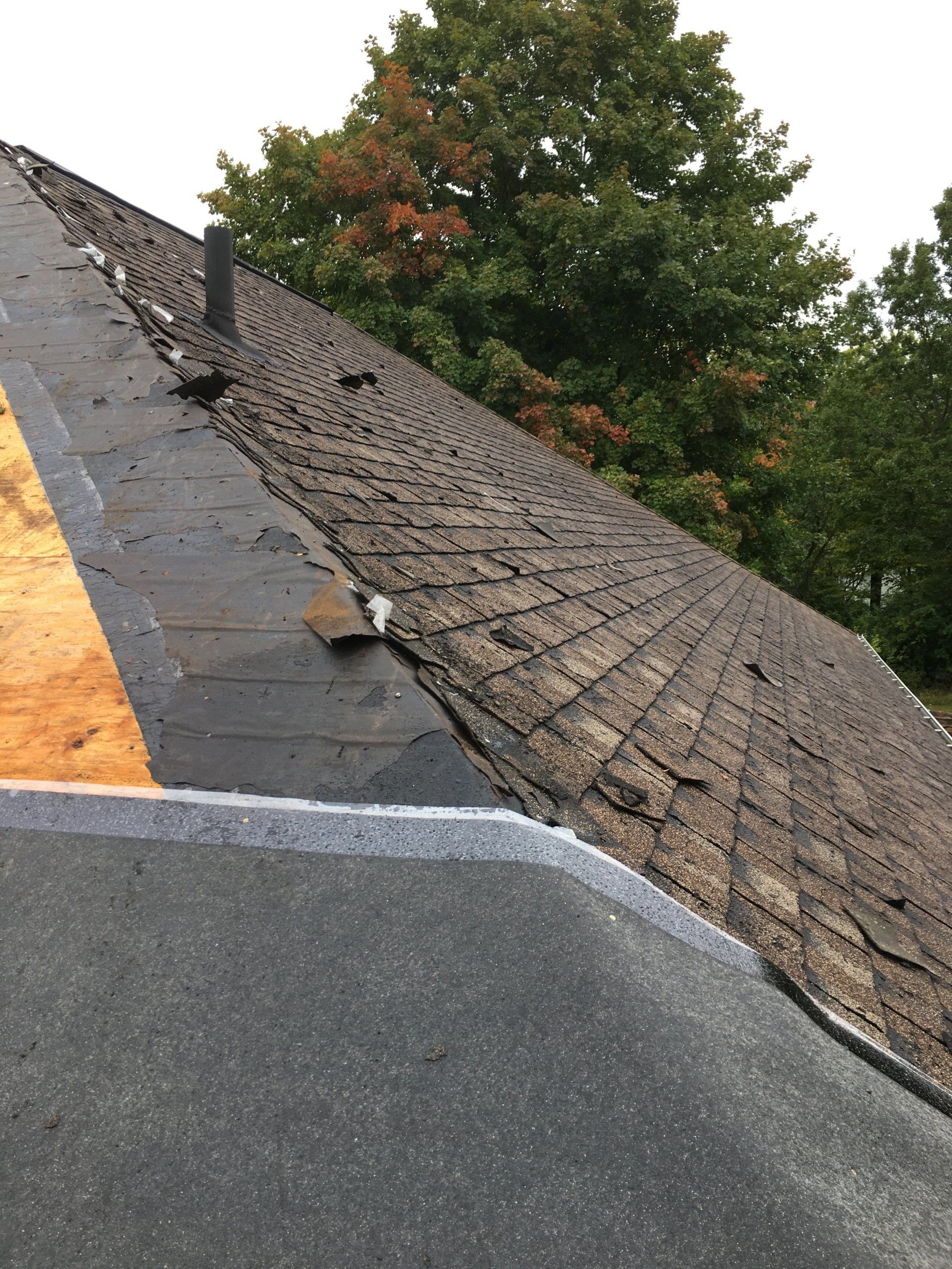 A roof with a lot of shingles on it and trees in the background.