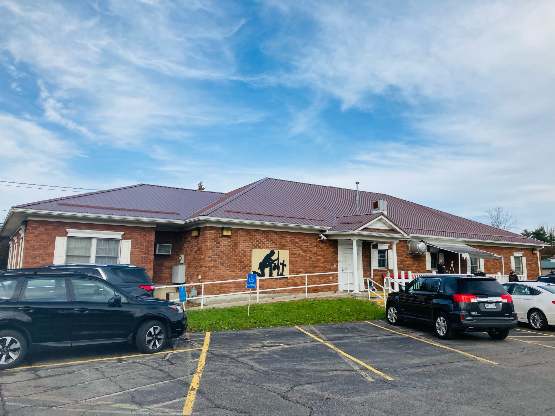 A brick building with a purple roof and cars parked in front of it.
