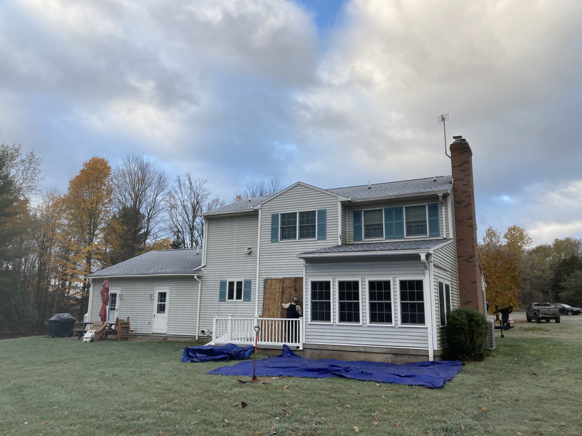 A large white house with a blue tarp in front of it