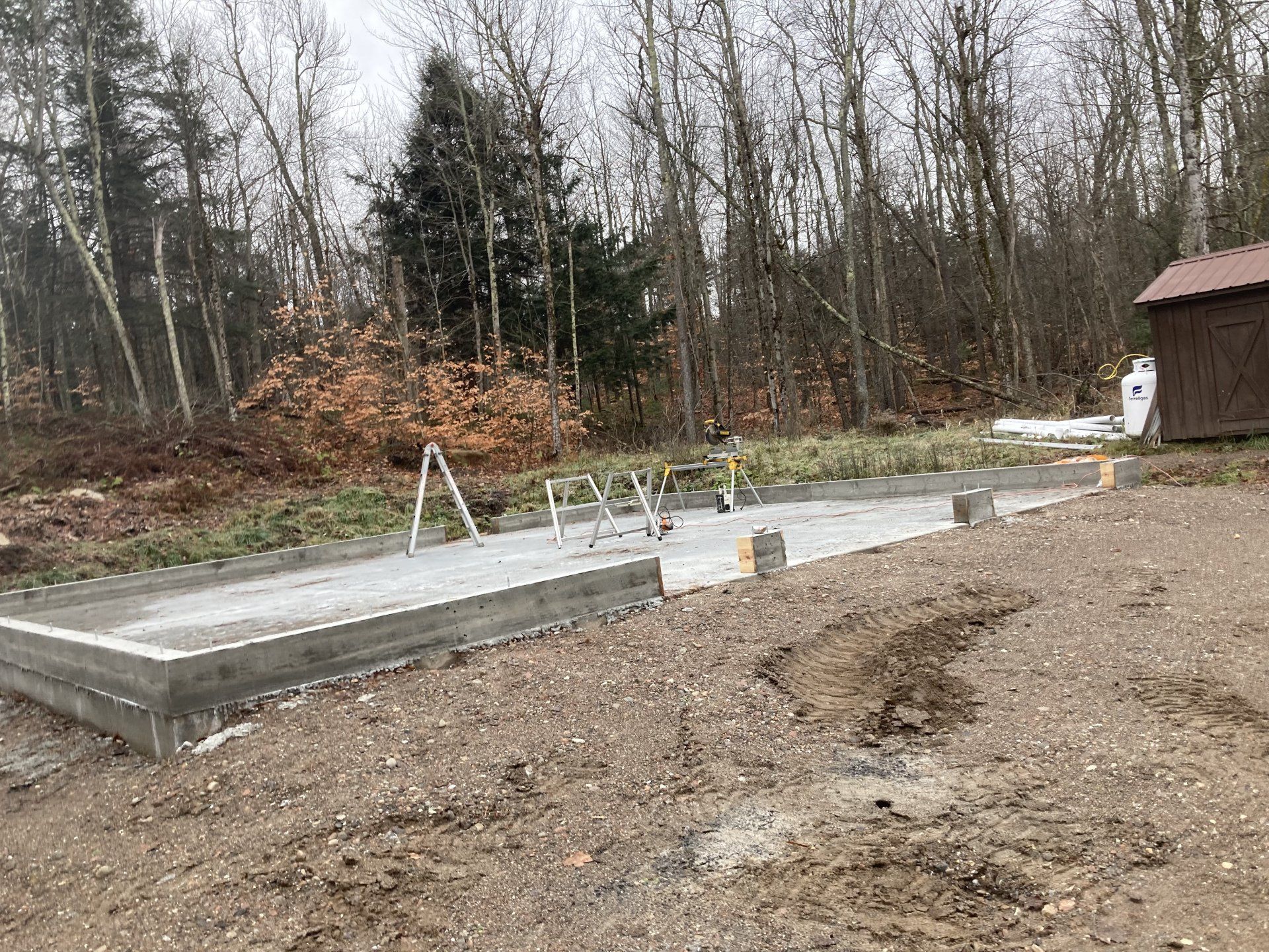 A concrete base for a house is being built in the woods.