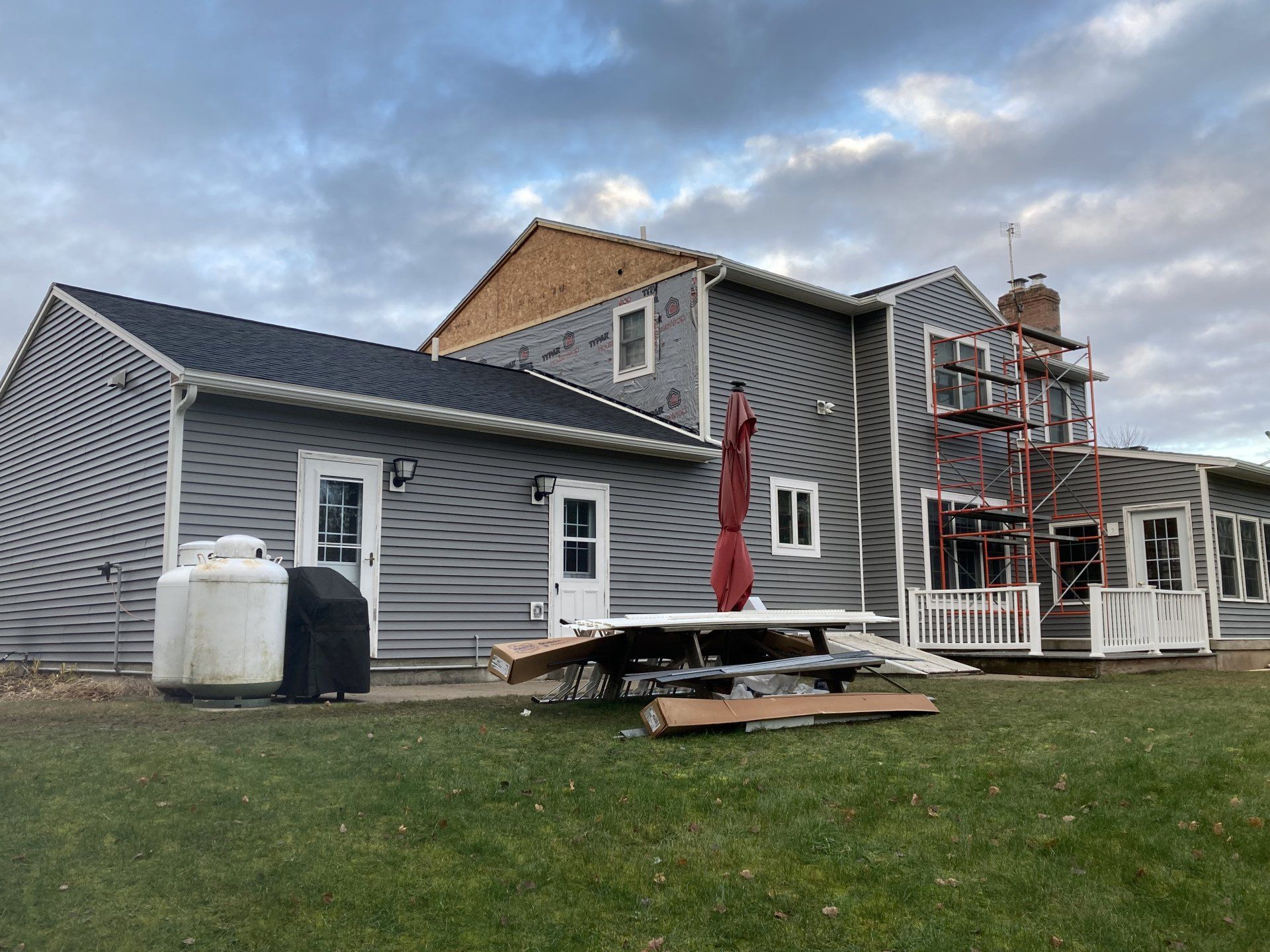 A large house with a picnic table and umbrella in front of it.