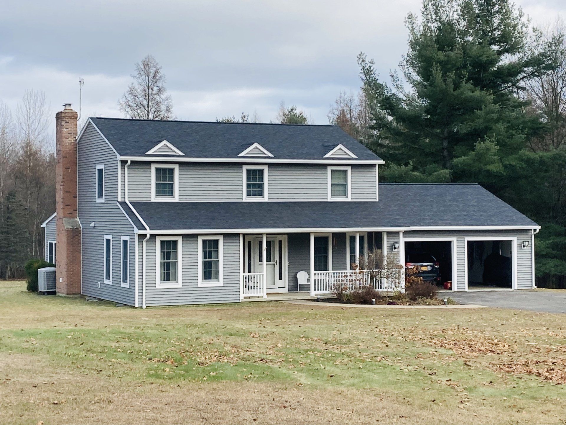 A gray house with a black roof and a garage