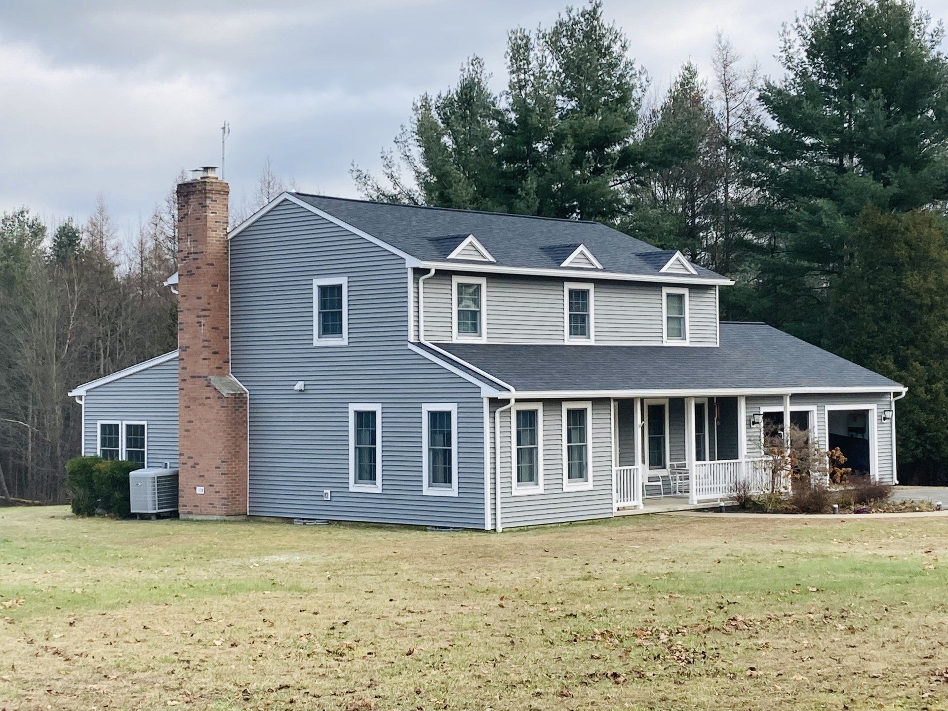 A large house in the middle of a field with trees in the background