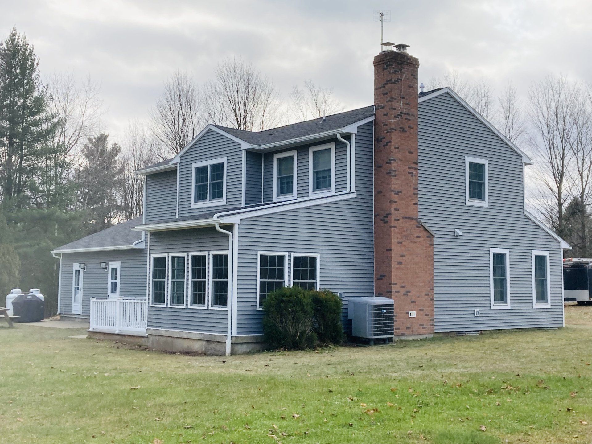 A large gray house with a brick chimney and a lot of windows