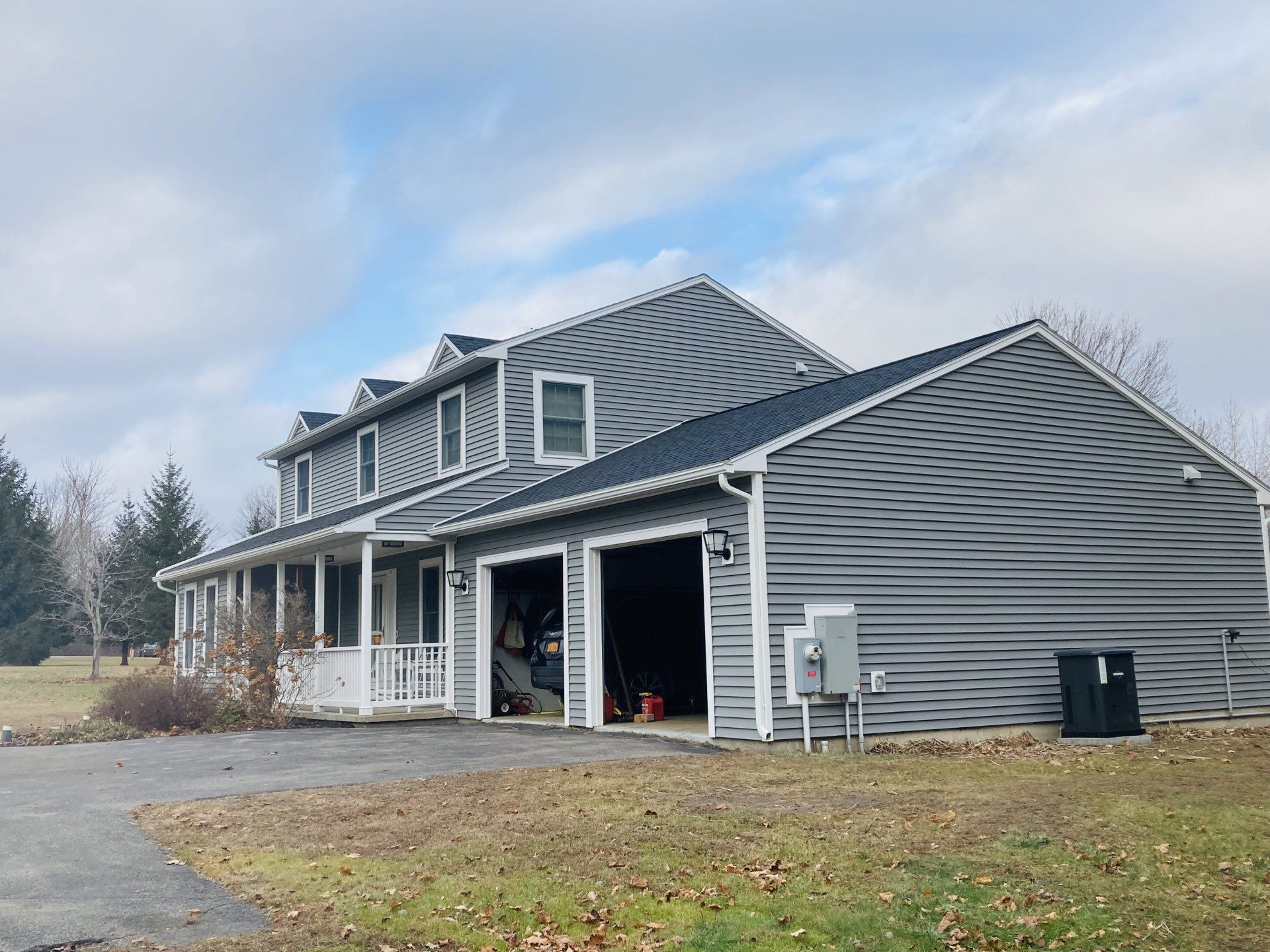 A large house with a garage and a porch on a sunny day.