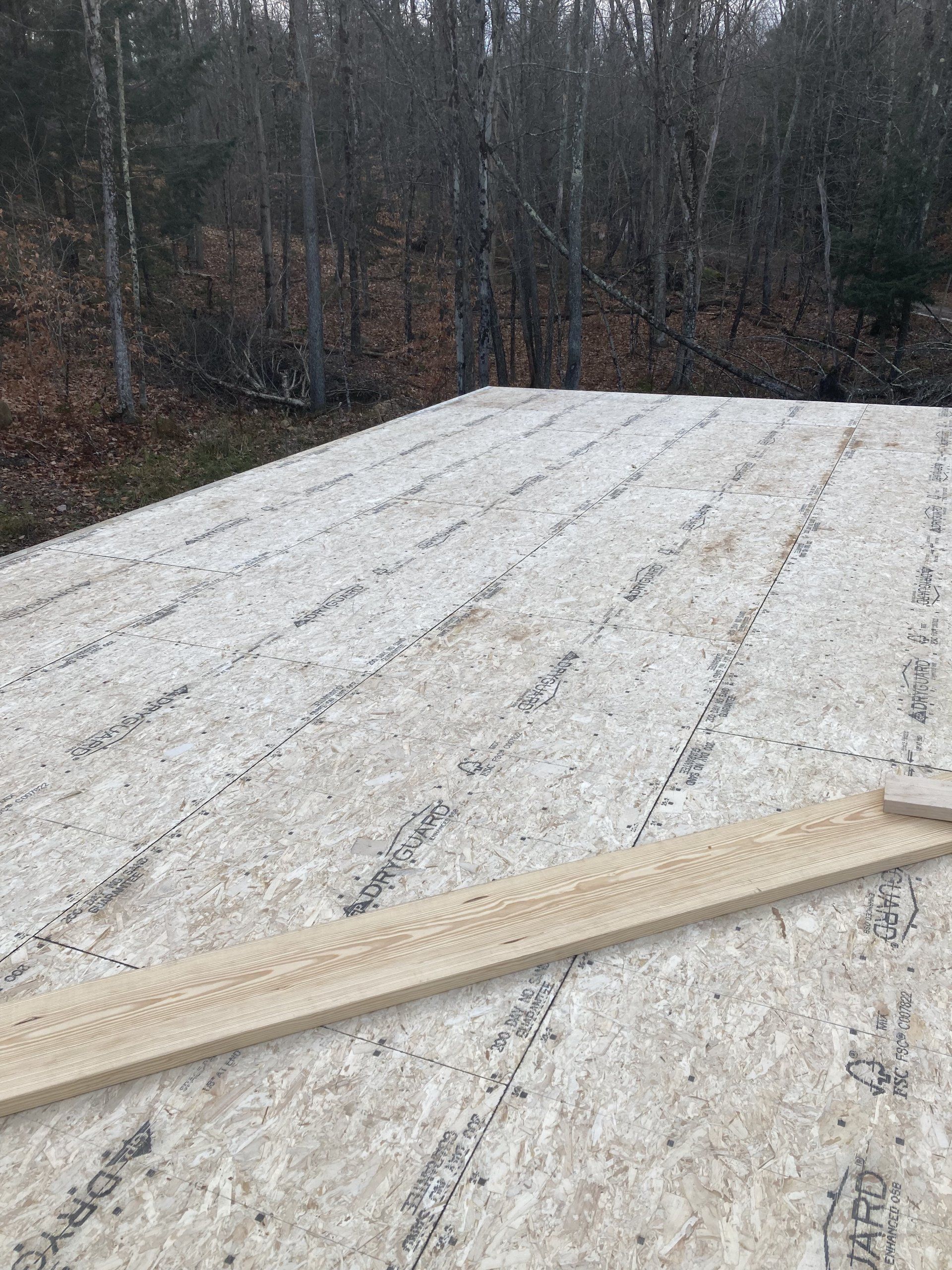 A wooden plank is laying on top of a pile of plywood.