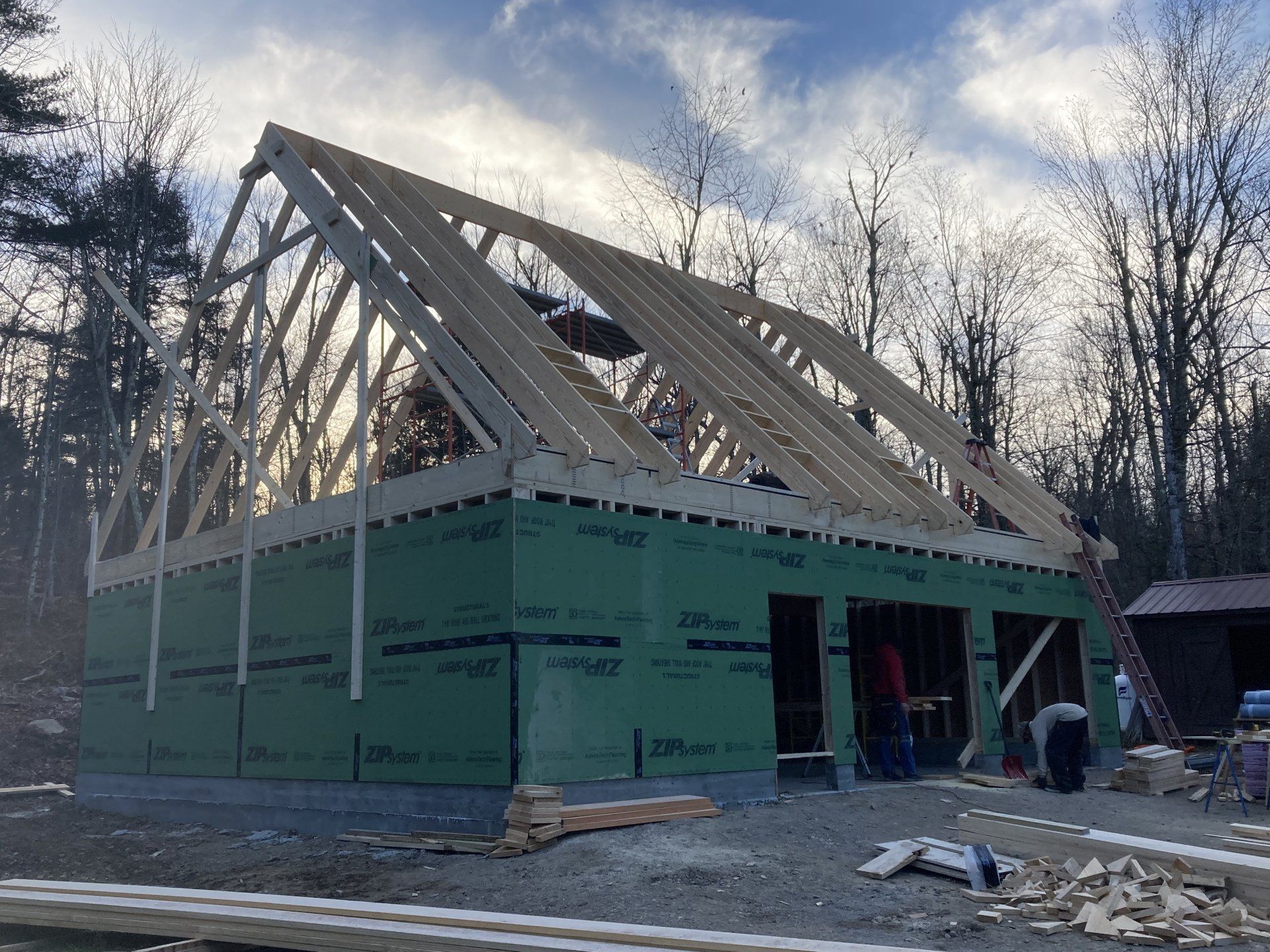 The roof of a building is being built in the woods.