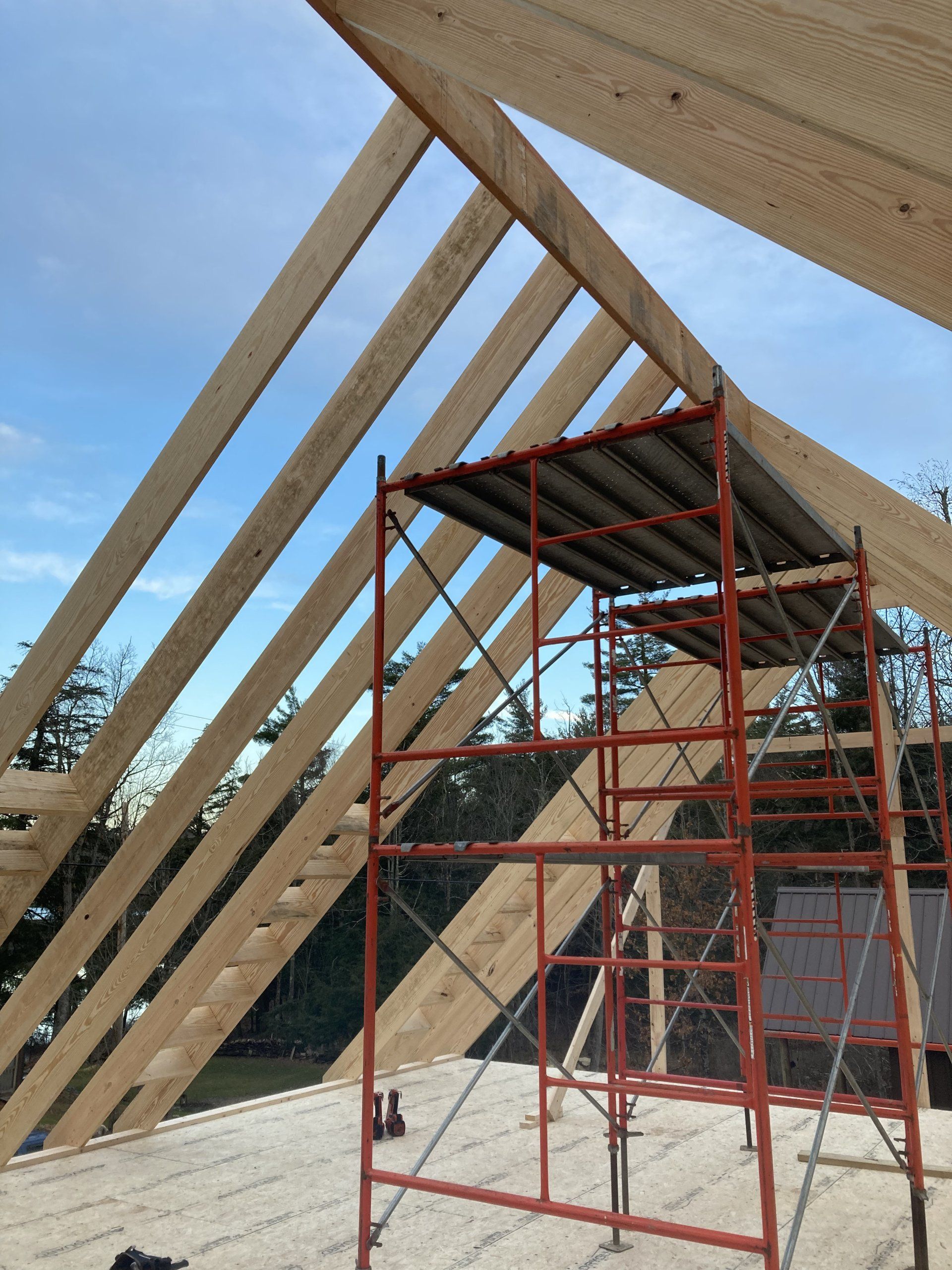 A red scaffolding is in front of a wooden roof