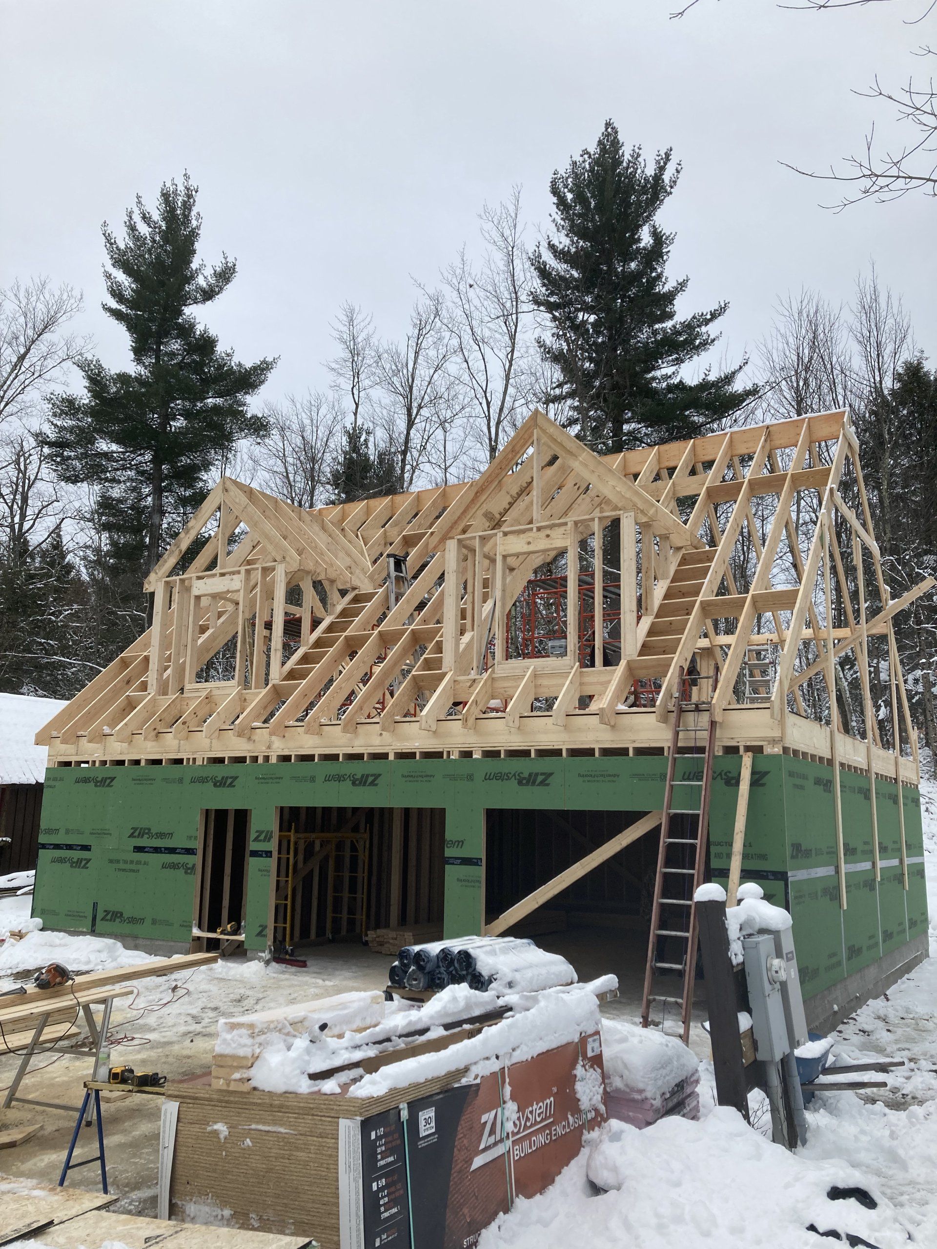 A house is being built in the snow and the roof is being built.