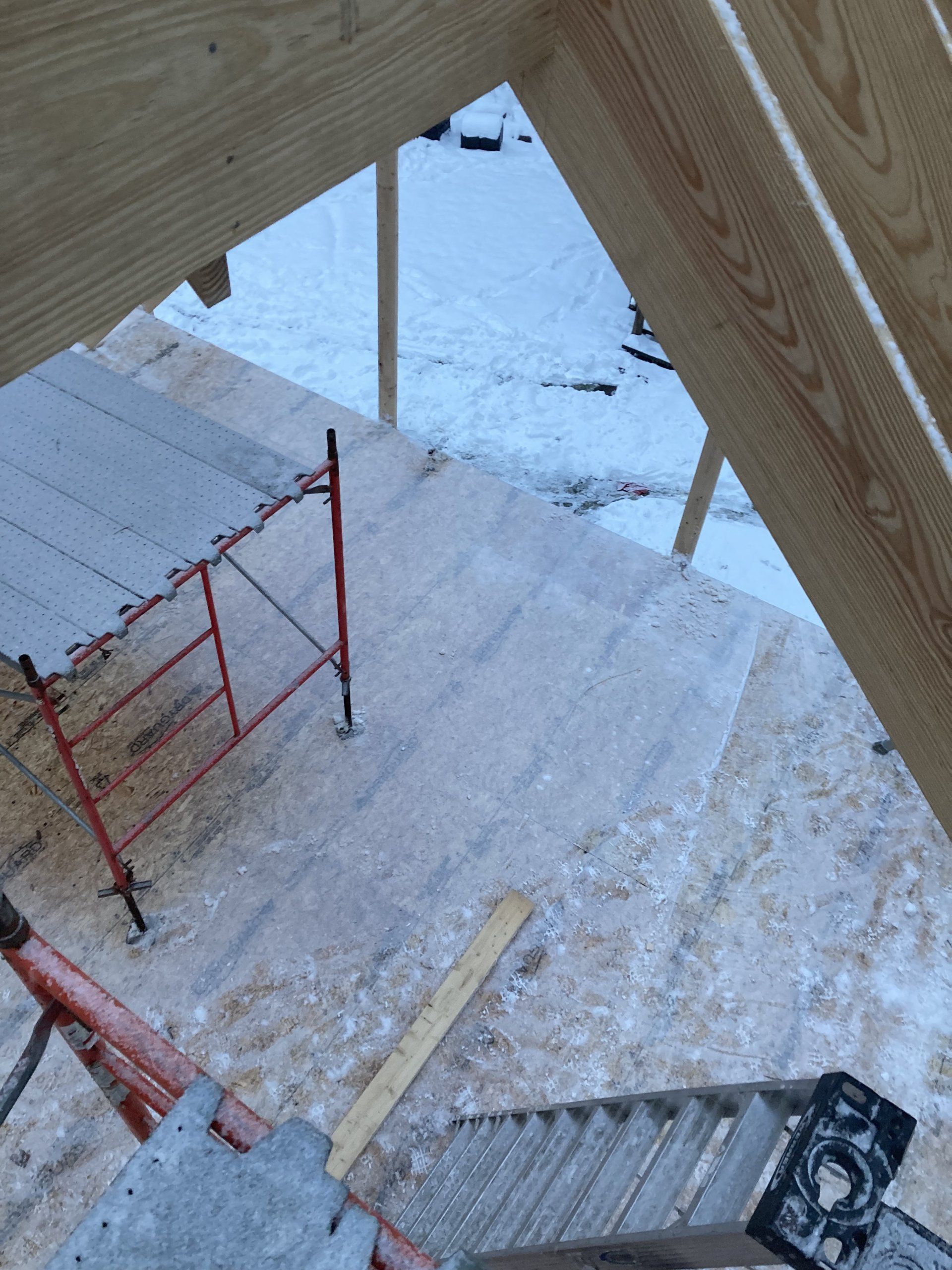 A ladder is sitting on the ground next to a wooden scaffolding