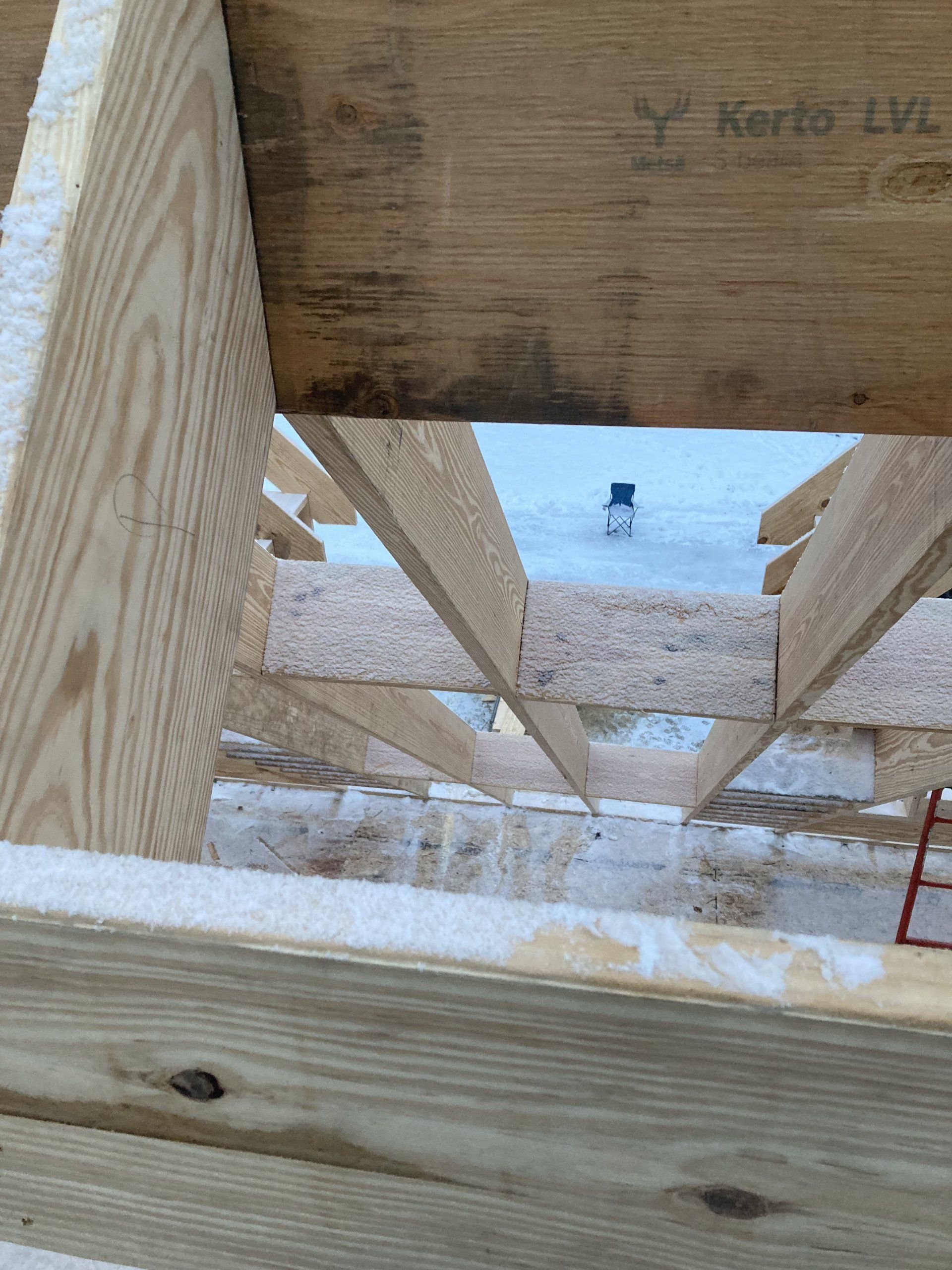 A close up of a wooden structure with a snowman in the background.