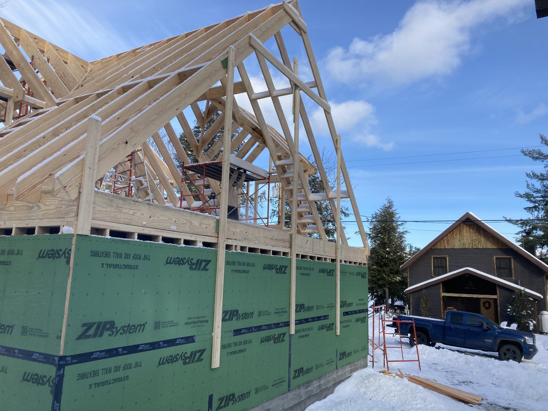 A blue truck is parked in front of a house under construction