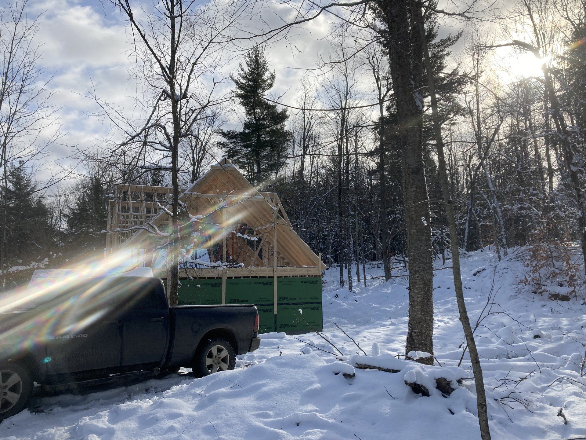 A truck is parked in the snow in front of a house under construction