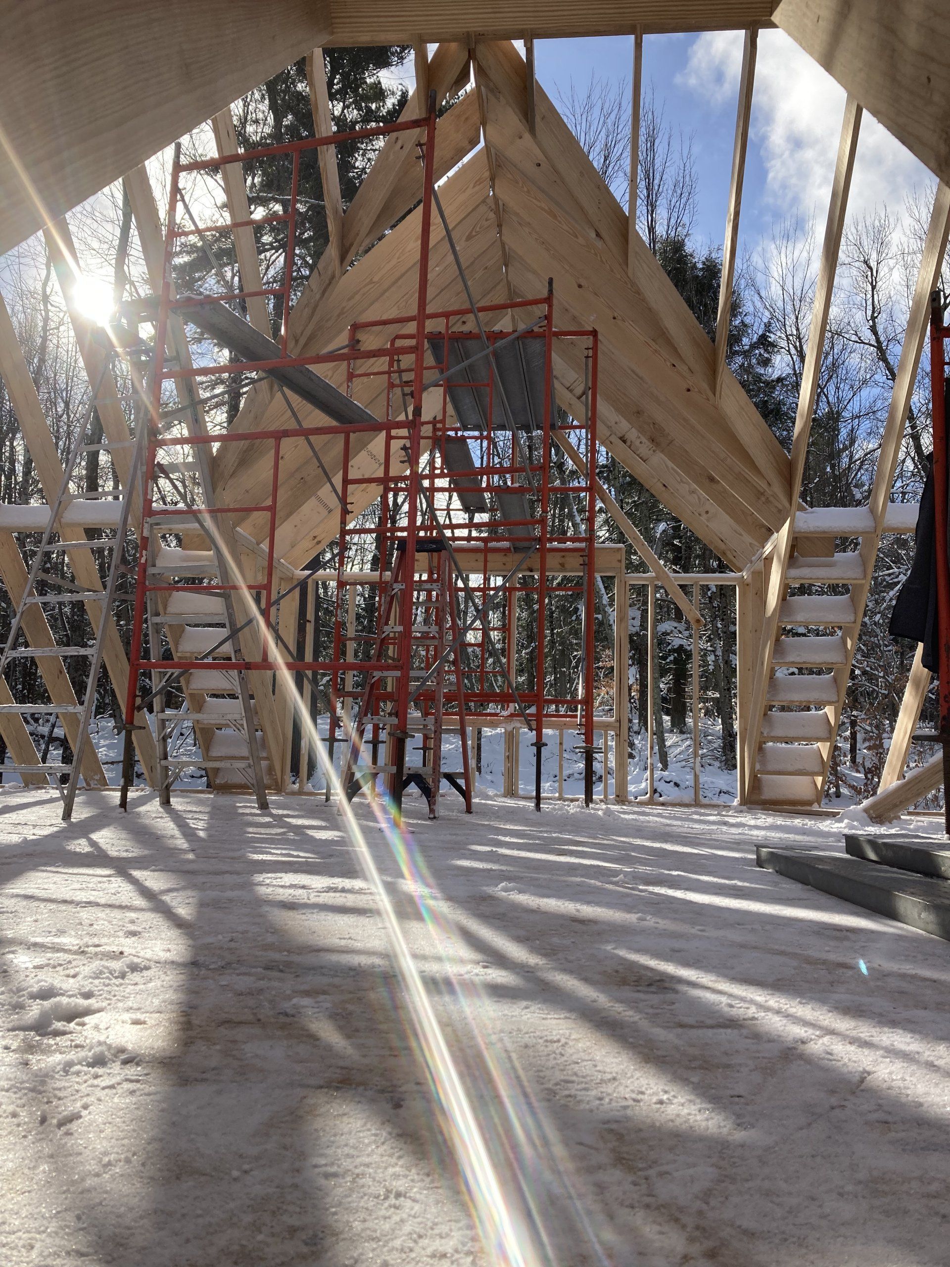 The sun is shining through the scaffolding in the snow
