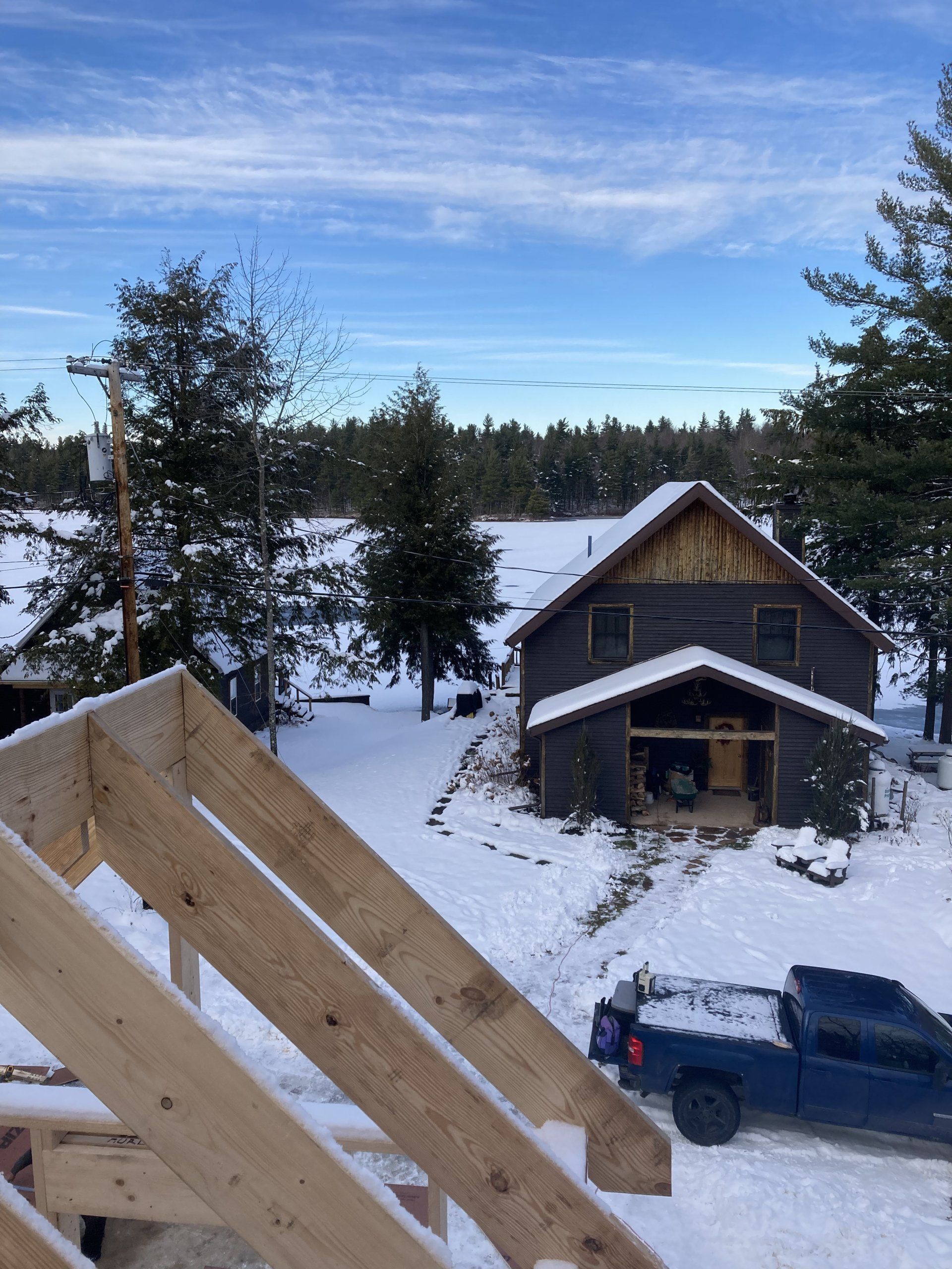 A blue truck is parked in front of a snow covered house