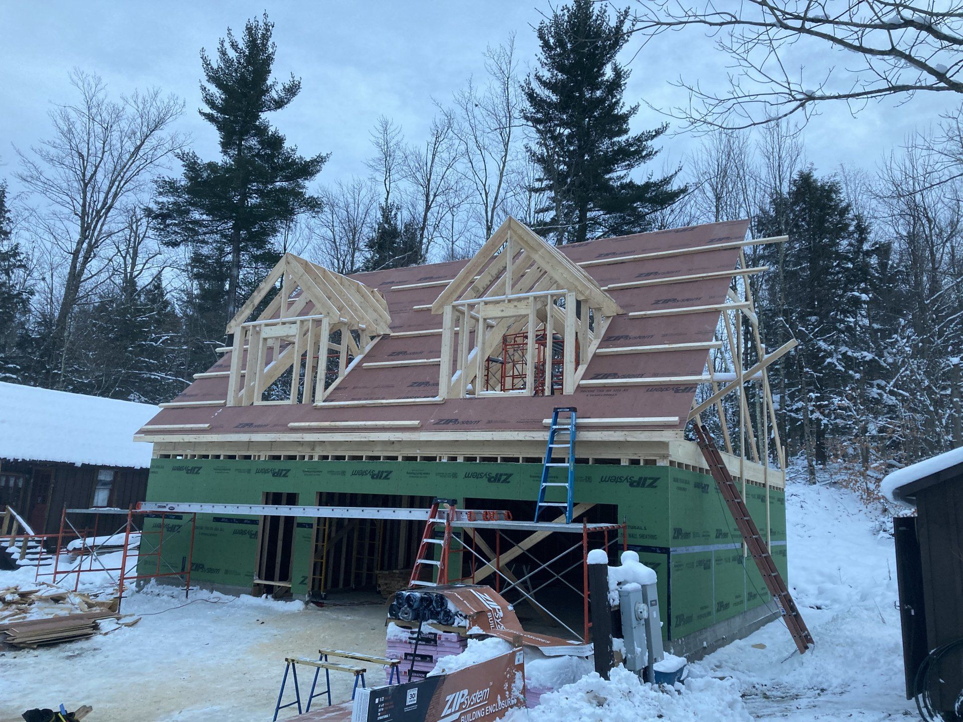 The roof of a house is being built in the snow.