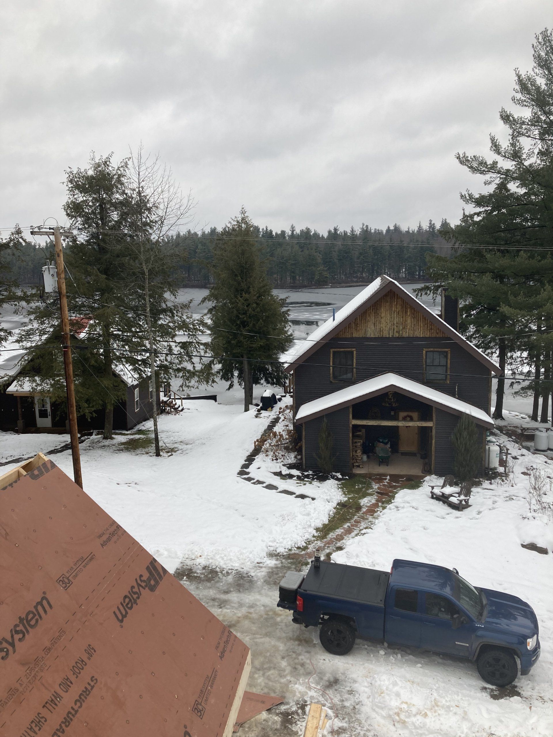 A blue truck is parked in front of a house in the snow.