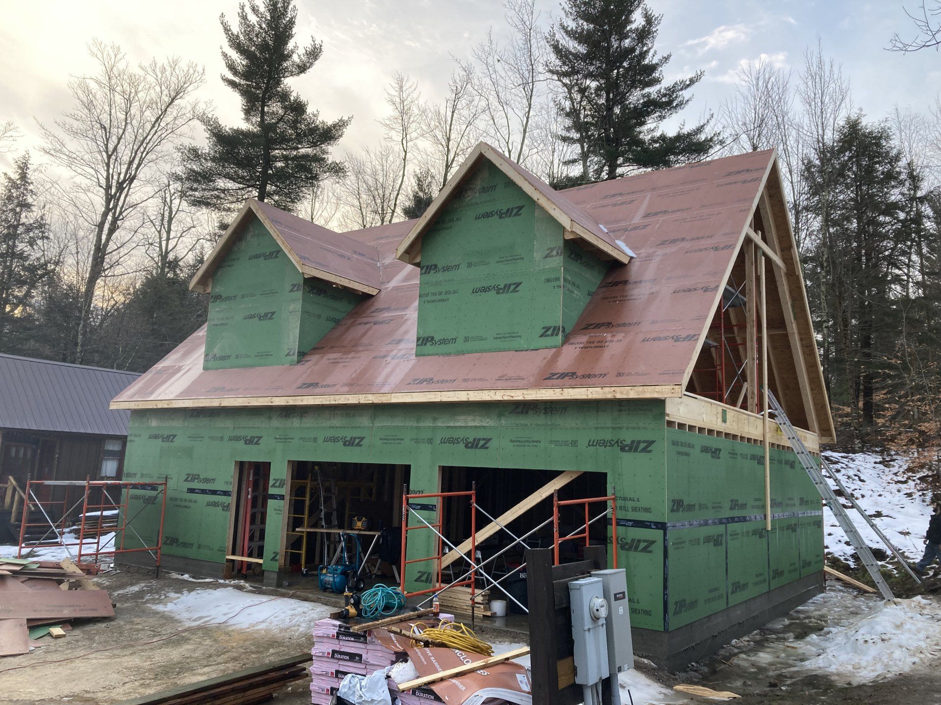 A house is being built in the woods with a red roof.