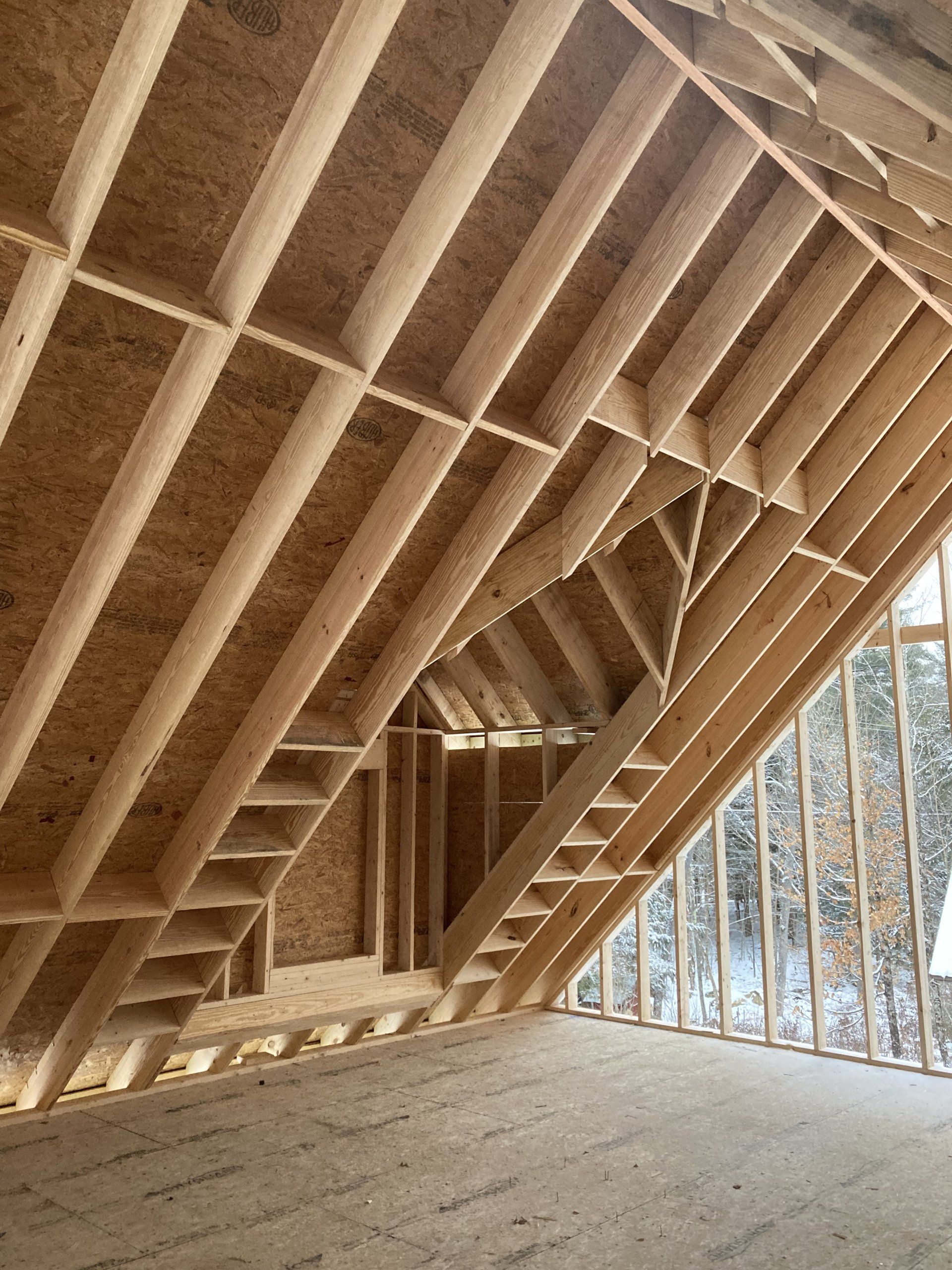 The ceiling of a house under construction with a lot of wooden beams.