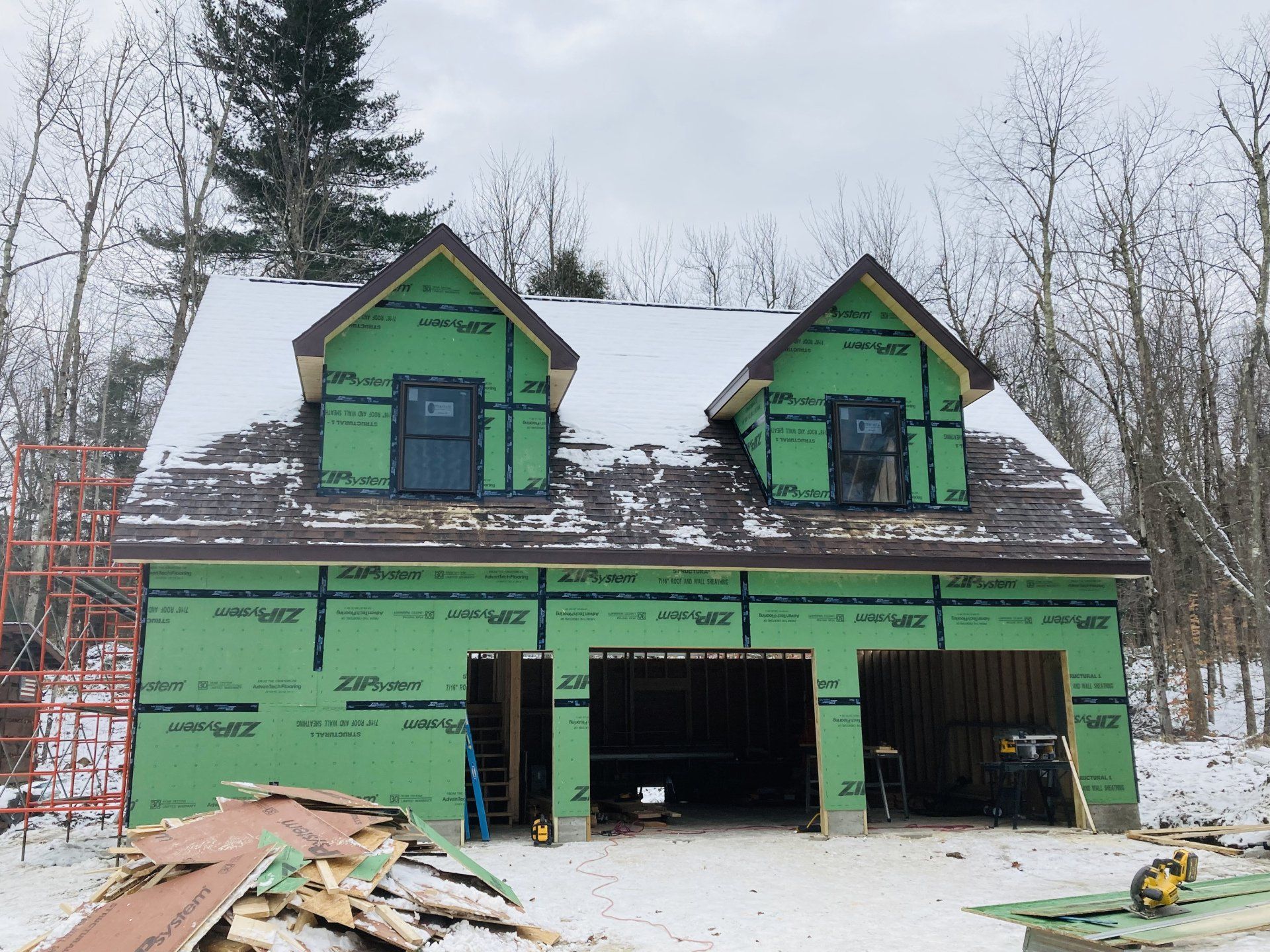 A house is being built in the snow with a green roof.