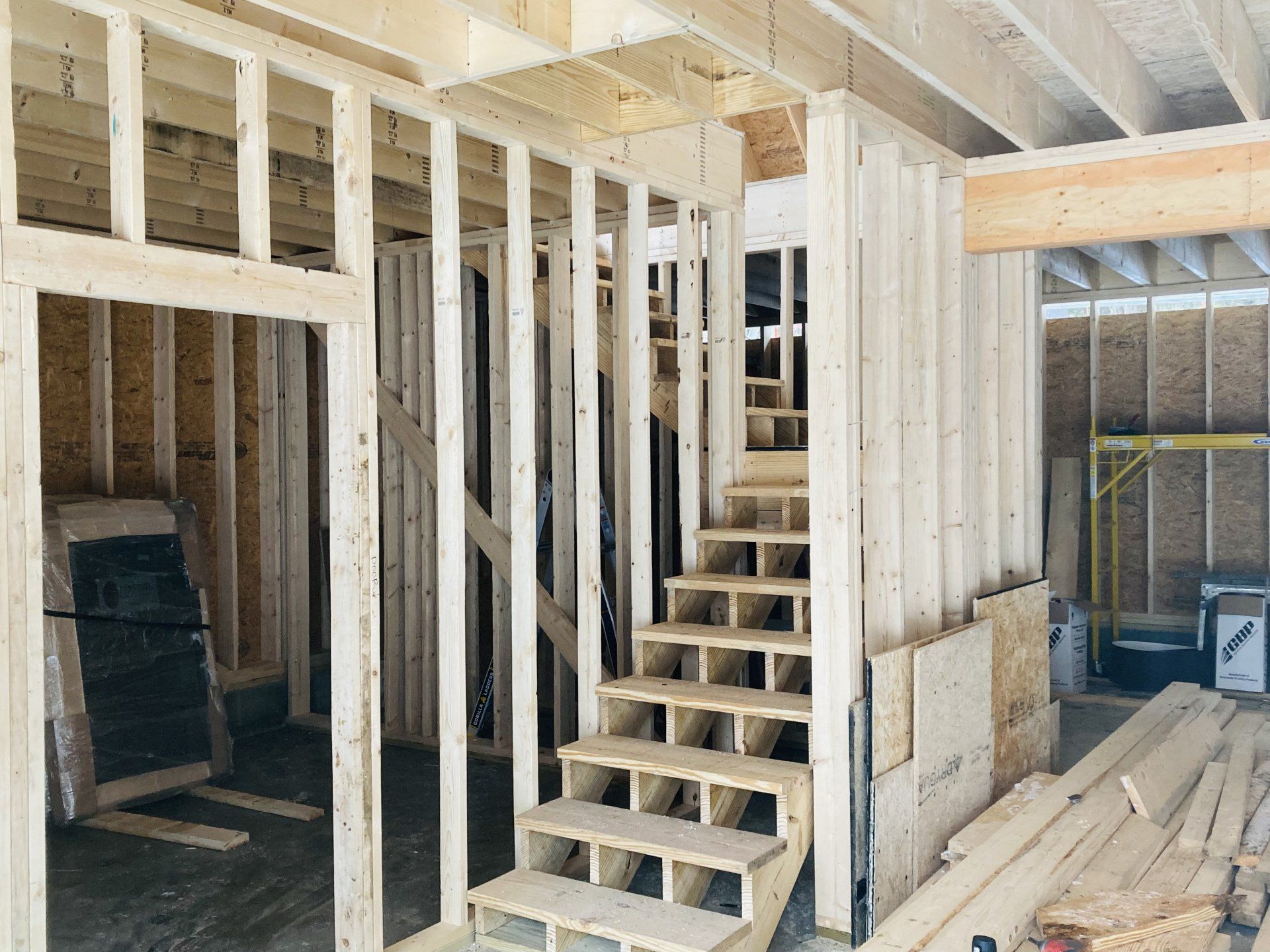 A wooden staircase is being built into a house under construction.