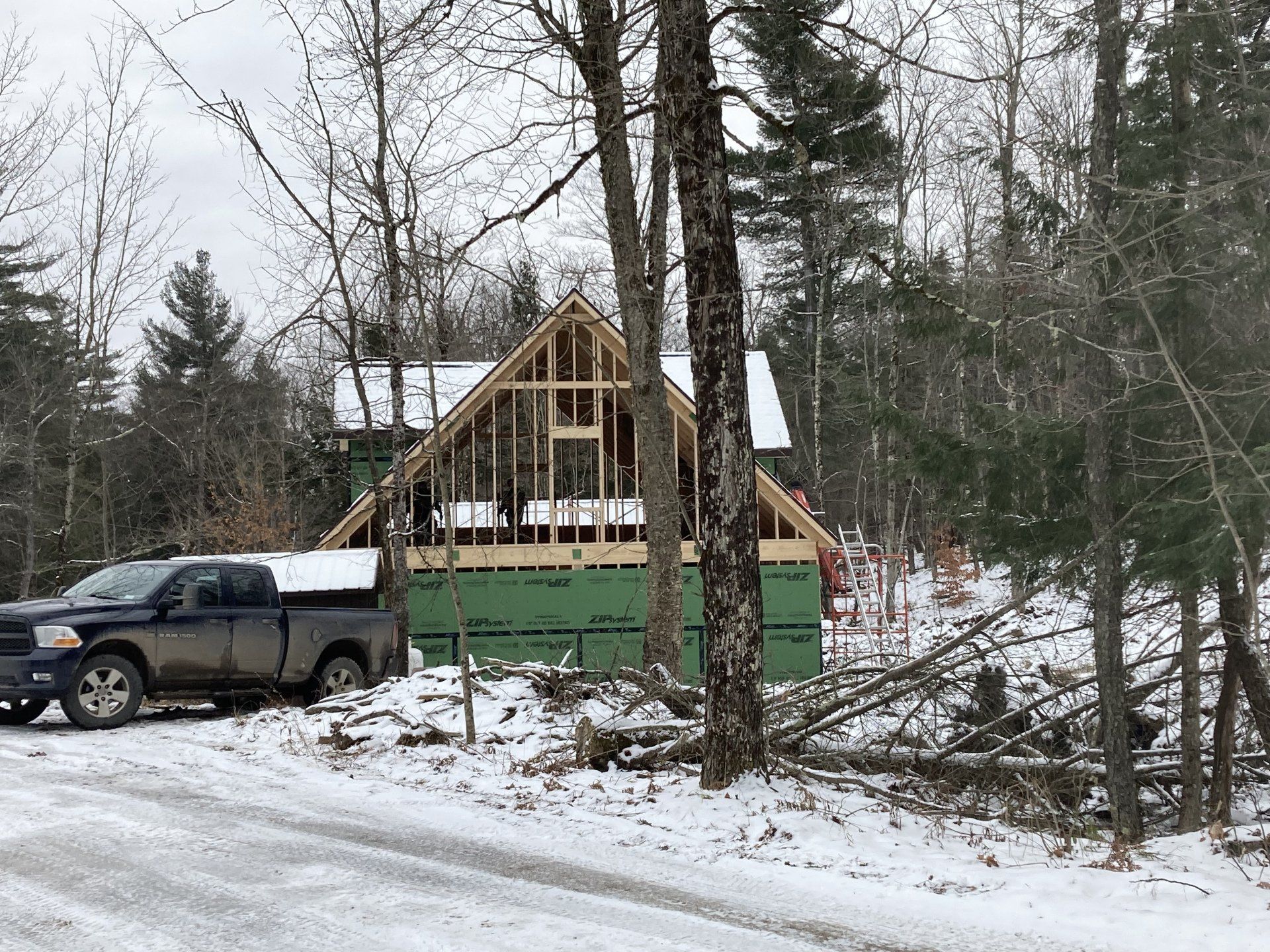 A truck is parked in front of a house under construction in the snow.