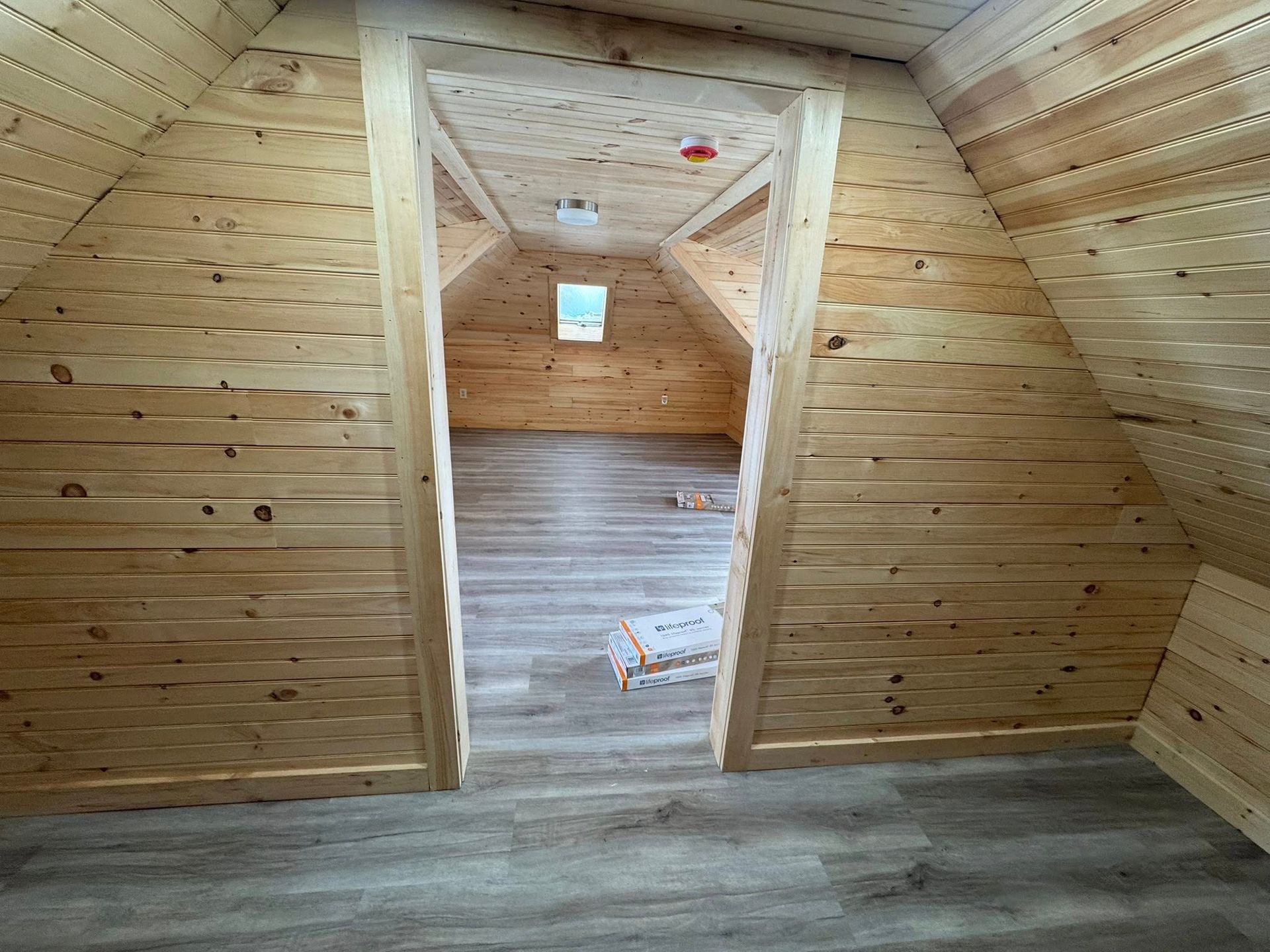 A small wooden shed with a window and a roof is being built.