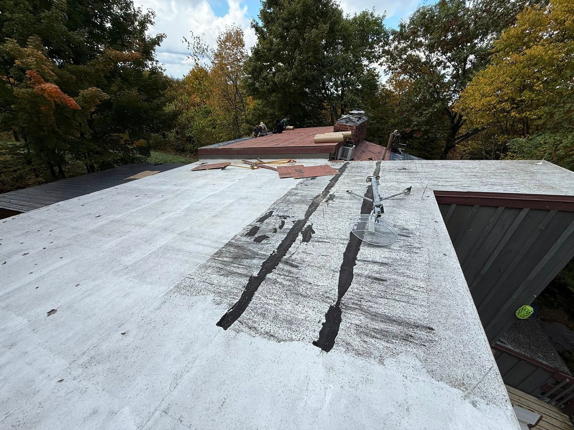 A man is sitting on a scaffolding on top of a brick building.