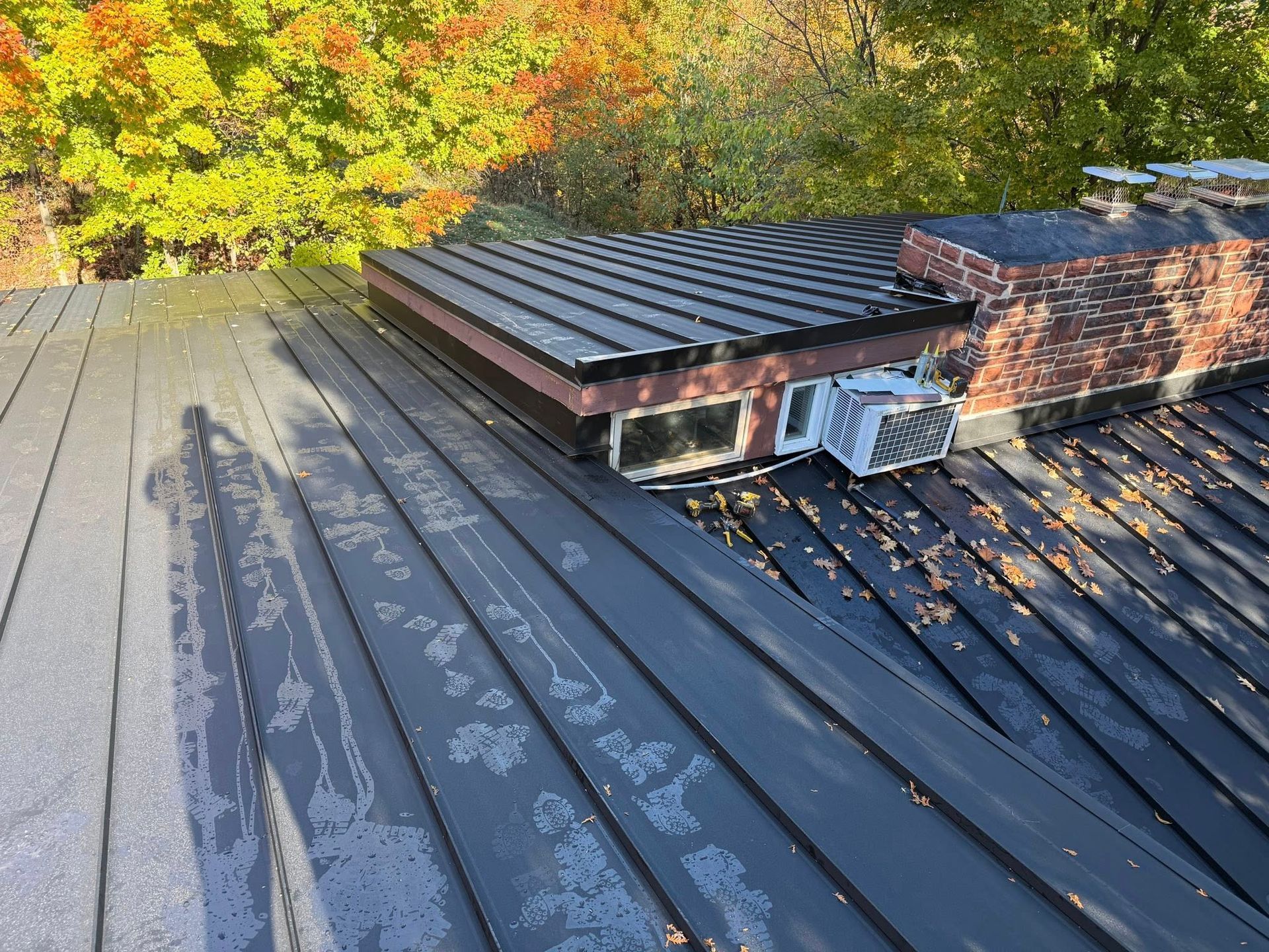 A man is standing on the roof of a brick house.