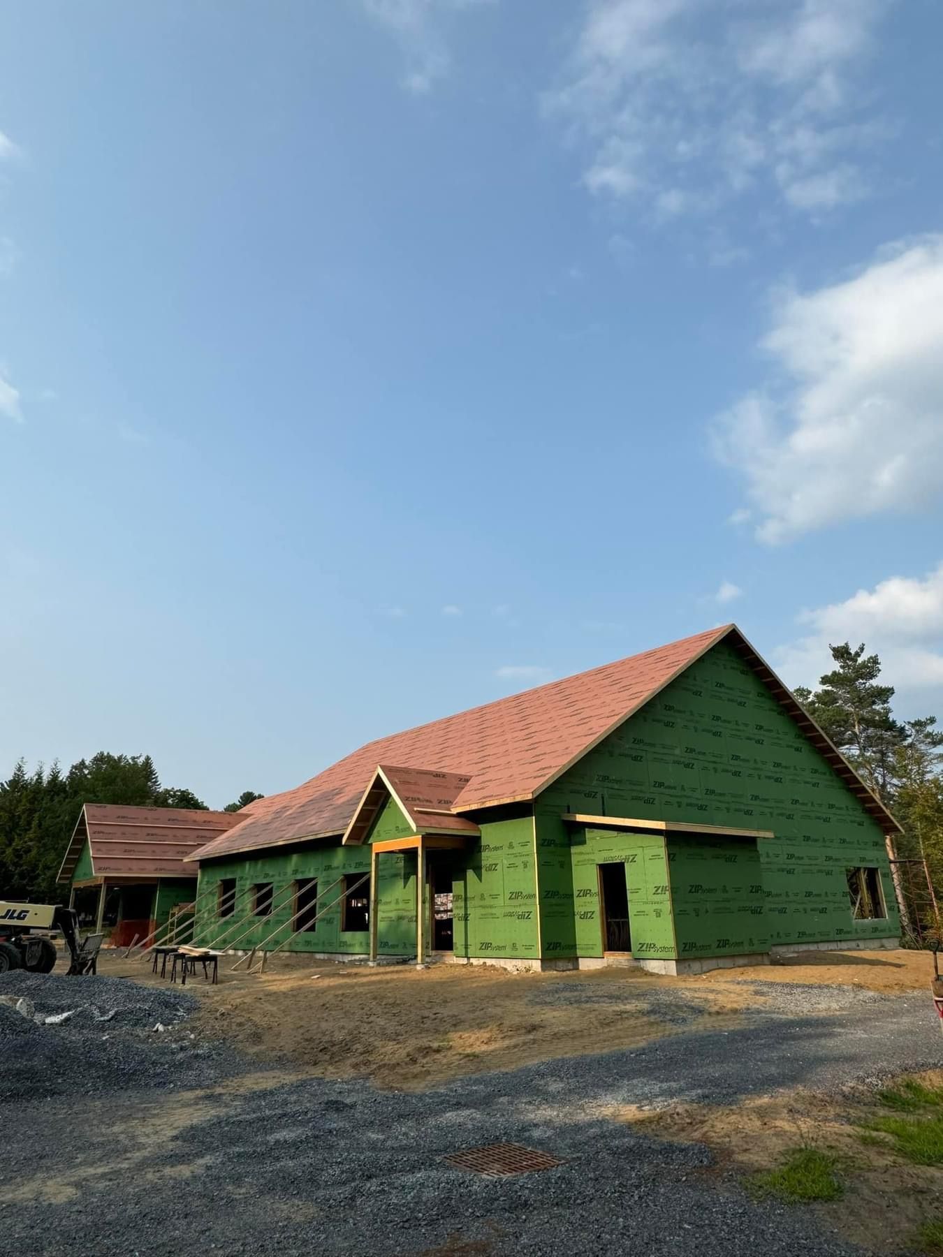 A house is being built with green siding and a red roof.