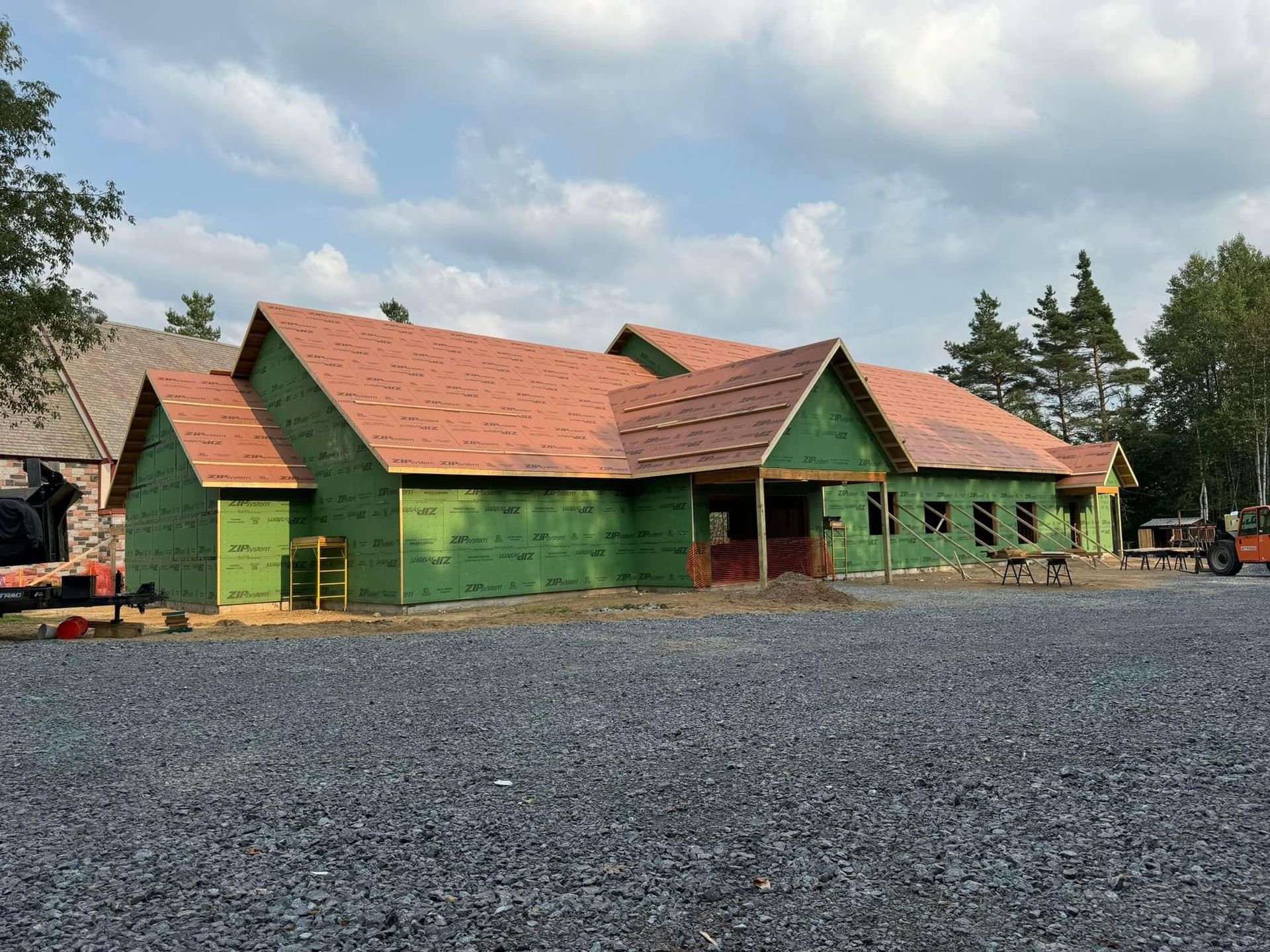 A large house is being built in a gravel lot.